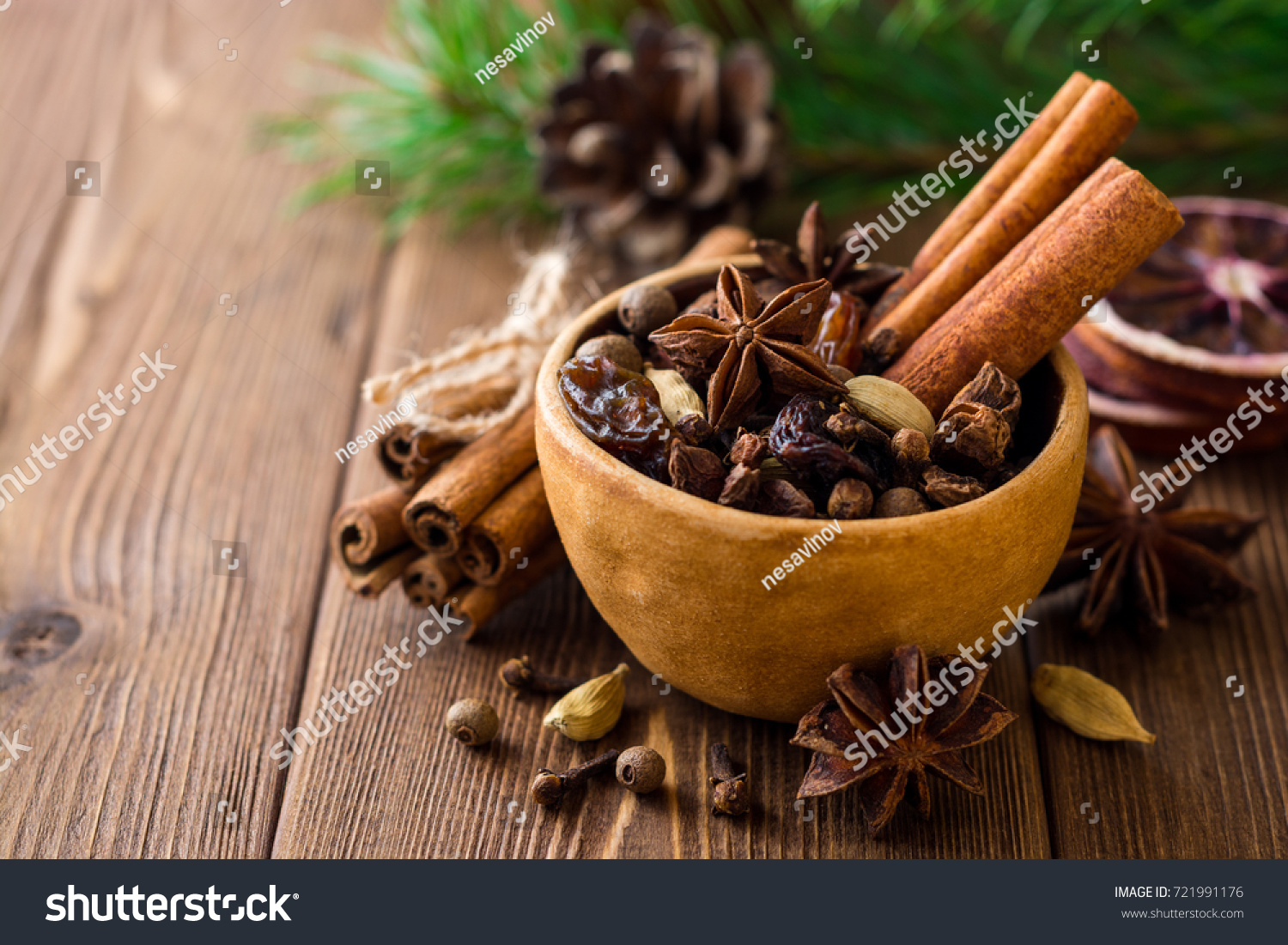 Set of spices for mulled wine in ceramic bowl on wooden table. Cinnamon sticks, star anise, cardamom, cloves, allspice and raisins. Selective focus. #721991176