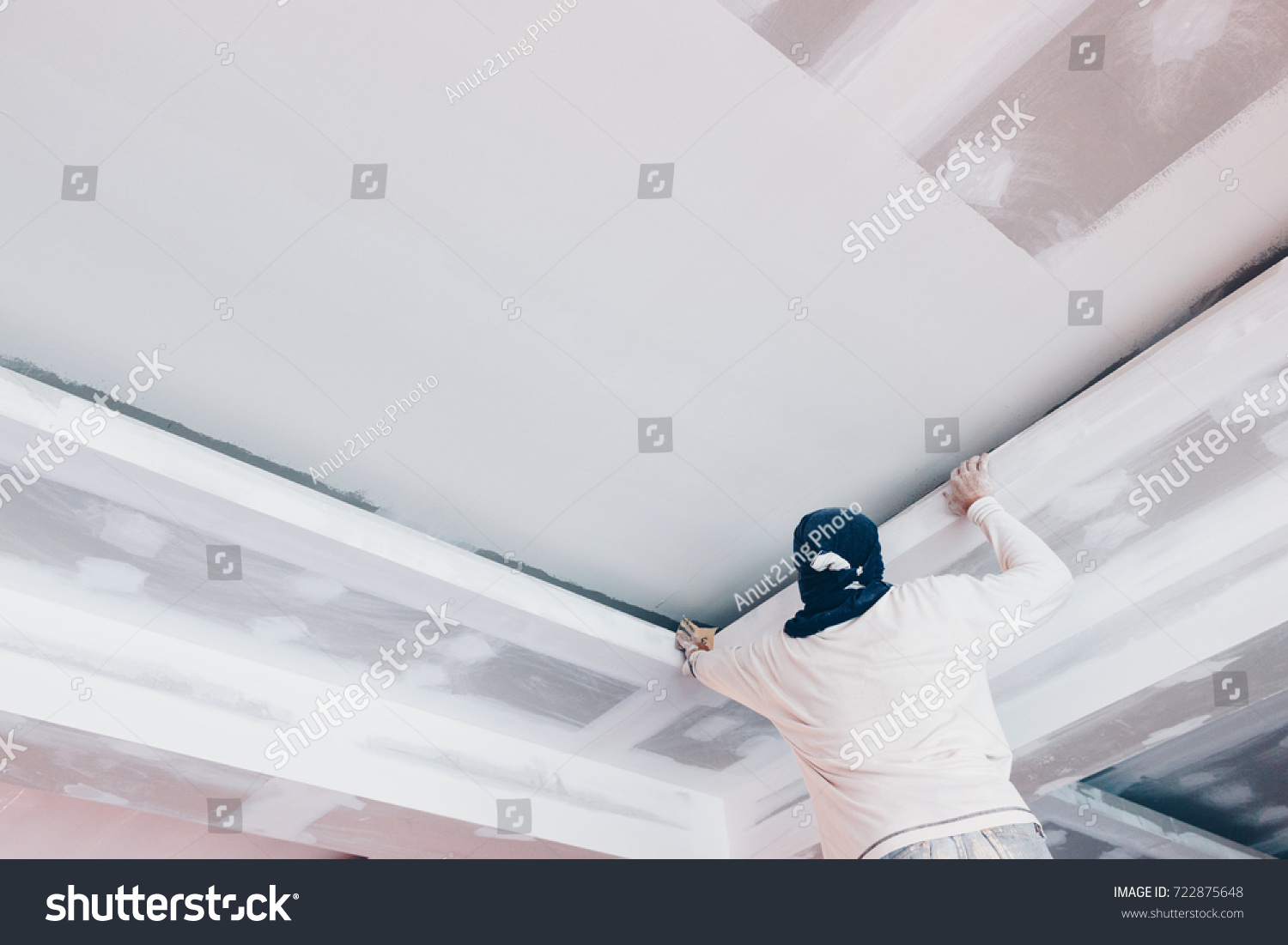 hand of worker using gypsum plaster ceiling joints at construction site #722875648