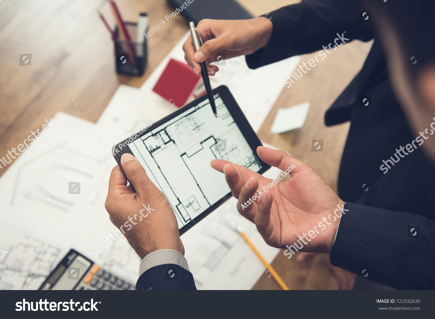 Real estate agent with client or architect team discussing a housing model and its blueprints digitally using a tablet computer #722932630