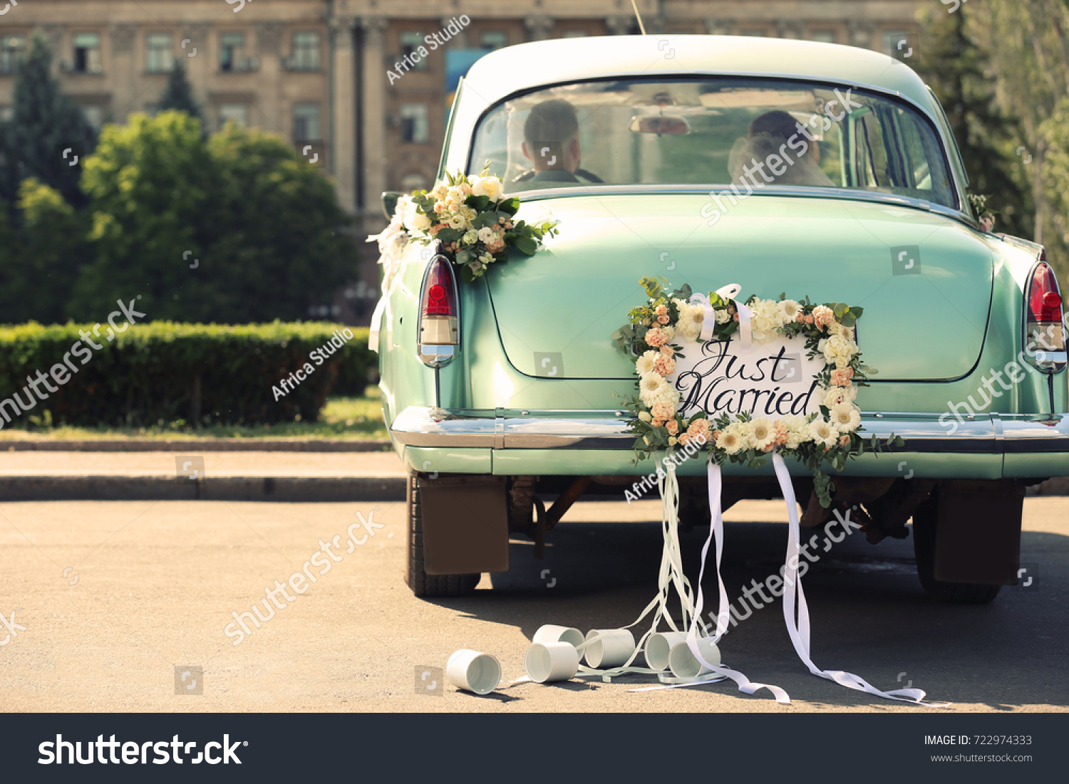 Wedding couple in car decorated with plate JUST MARRIED and cans outdoors #722974333
