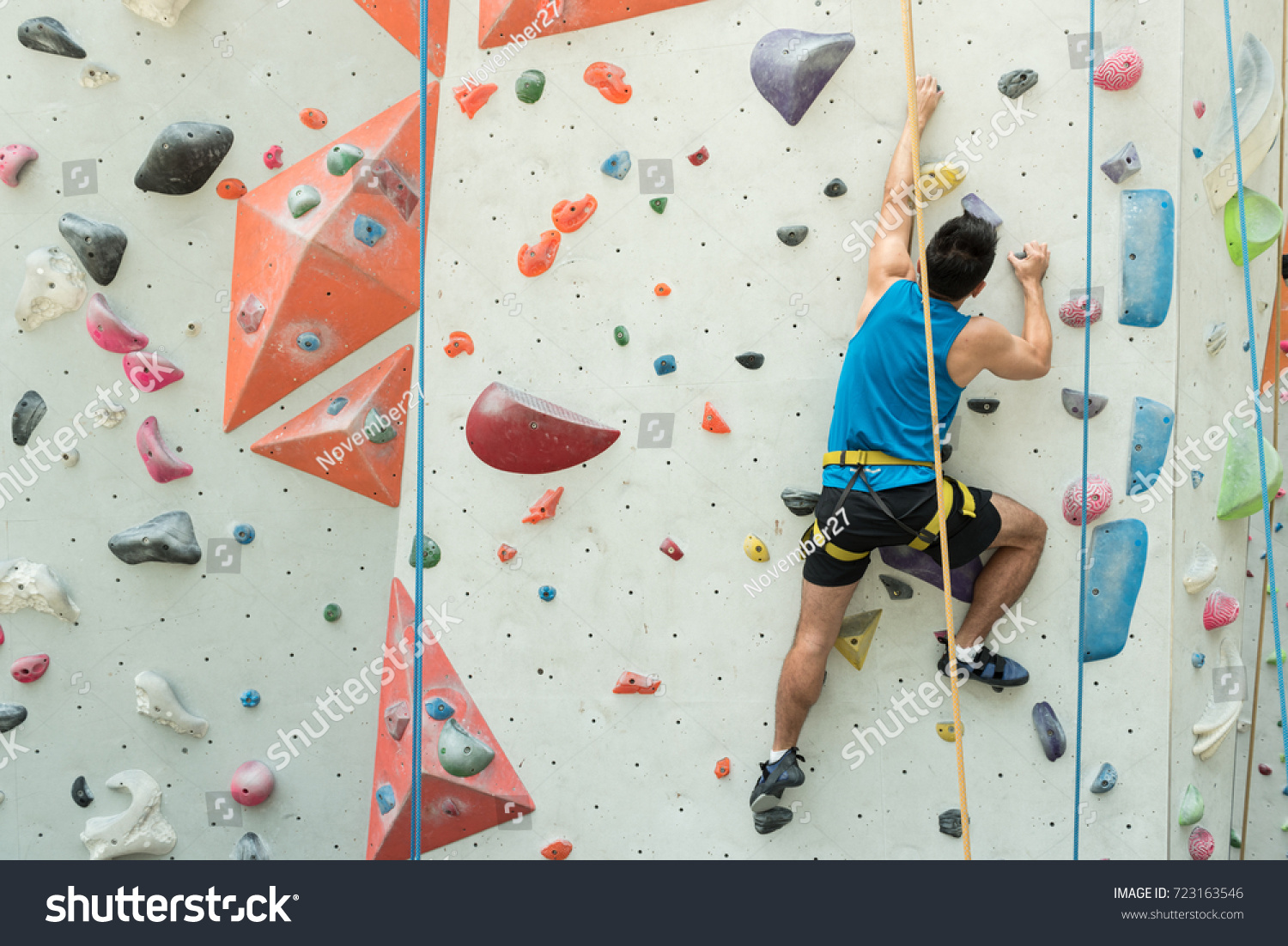Fit asian man rock climbing indoors at the gym #723163546