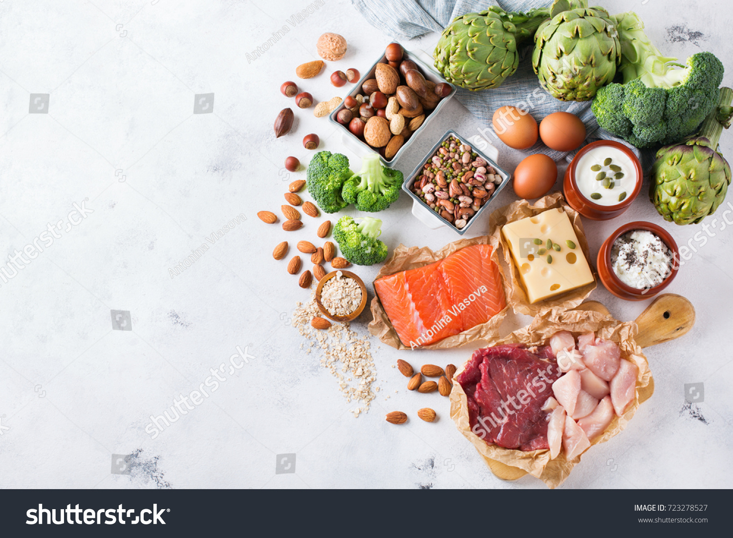 Assortment of healthy protein source and body building food. Meat beef salmon chicken breast eggs dairy products cheese yogurt beans artichokes broccoli nuts oat meal. Copy space background, top view #723278527
