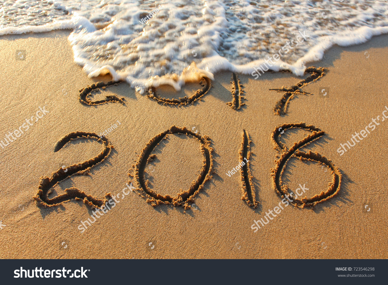 2018 year written on sandy beach sea. Inscription 2017 washes off wave. #723546298