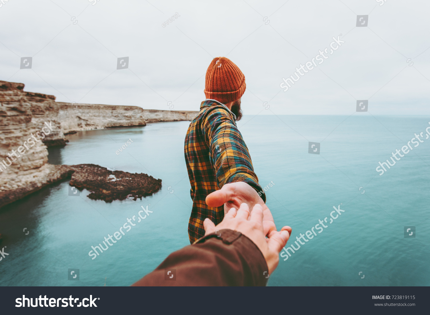 Couple Man and Woman holding hands follow enjoying cold sea landscape on background Love and Travel emotions Lifestyle concept. Young family traveling active adventure vacations.  #723819115