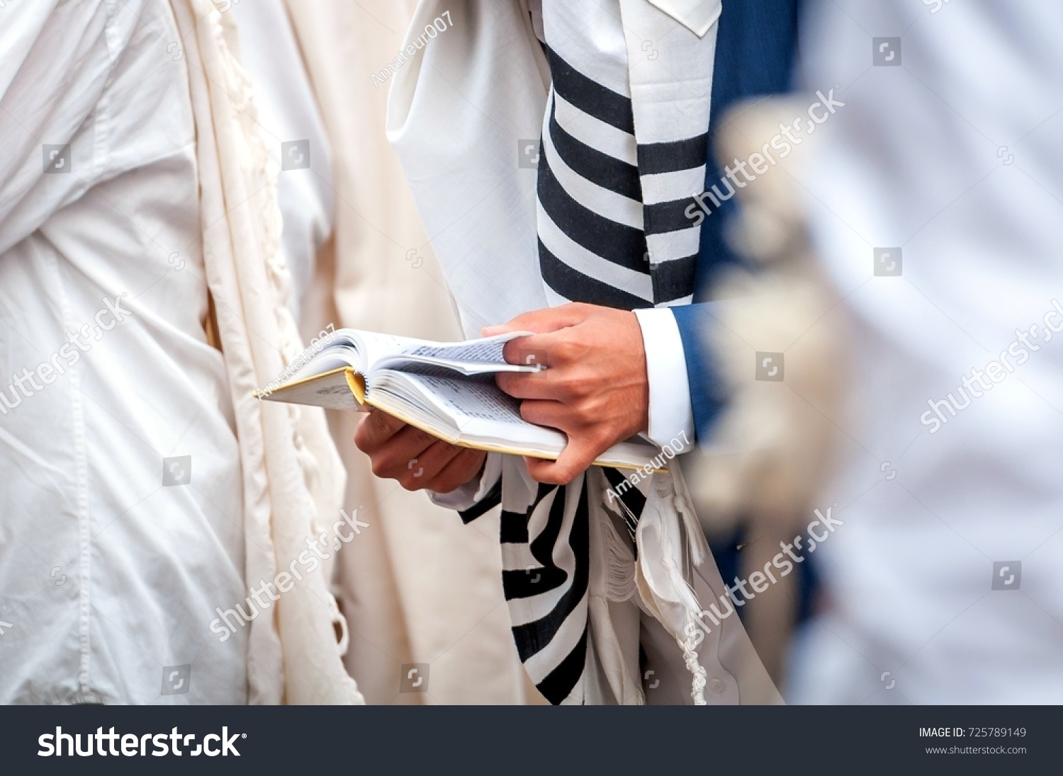 Hands and prayer book close-up. Orthodox hassidic Jews pray in a holiday robe and tallith #725789149