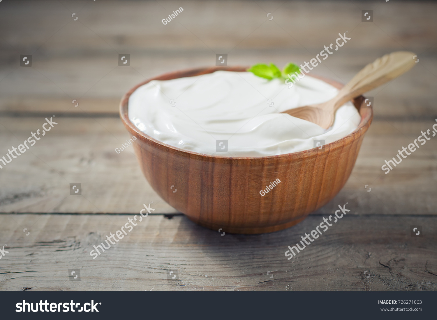 Greek yogurt in a wooden bowl on a rustic wooden table. Selective focus #726271063