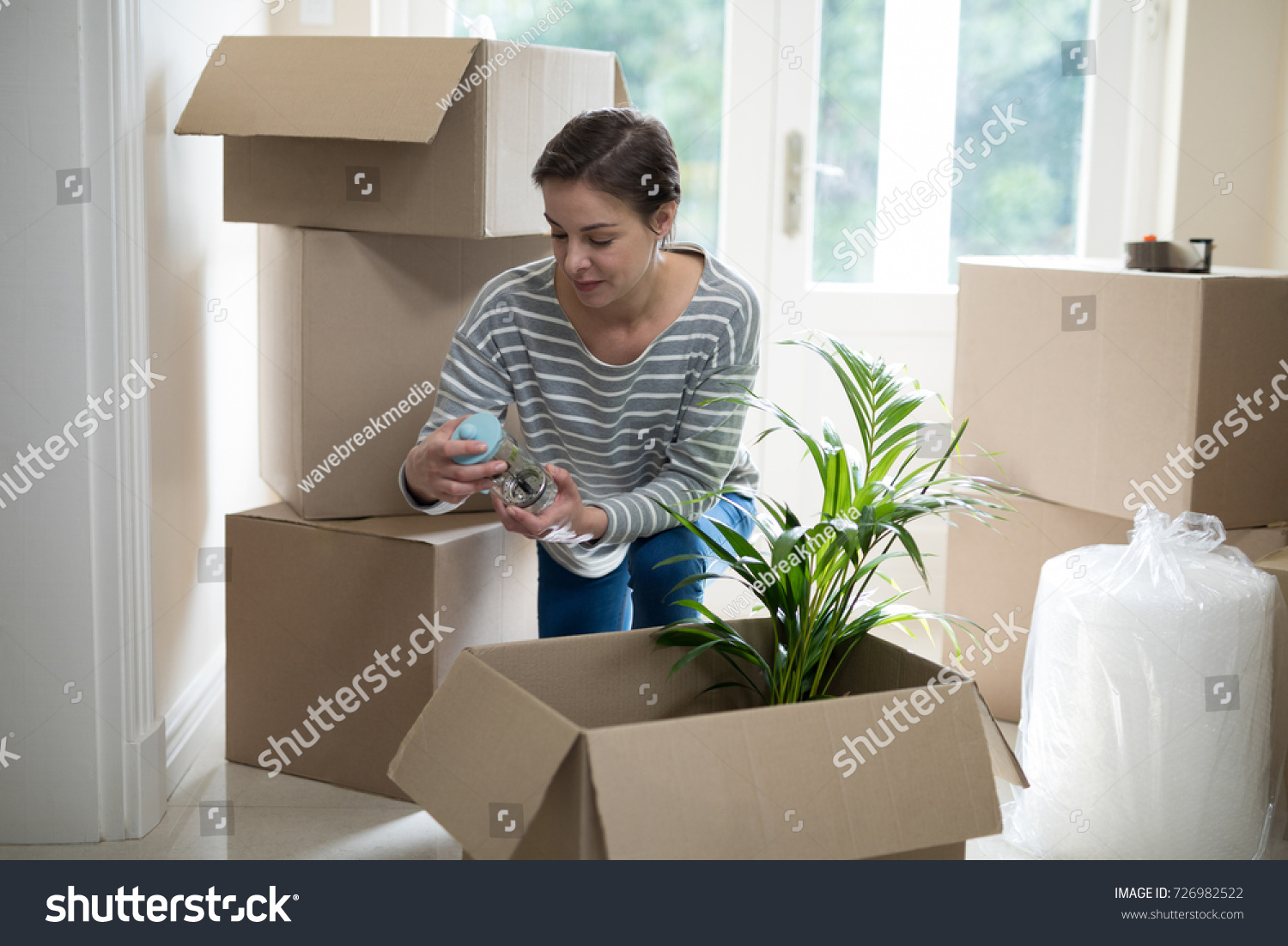 Woman opening cardboard boxes in living room at home #726982522
