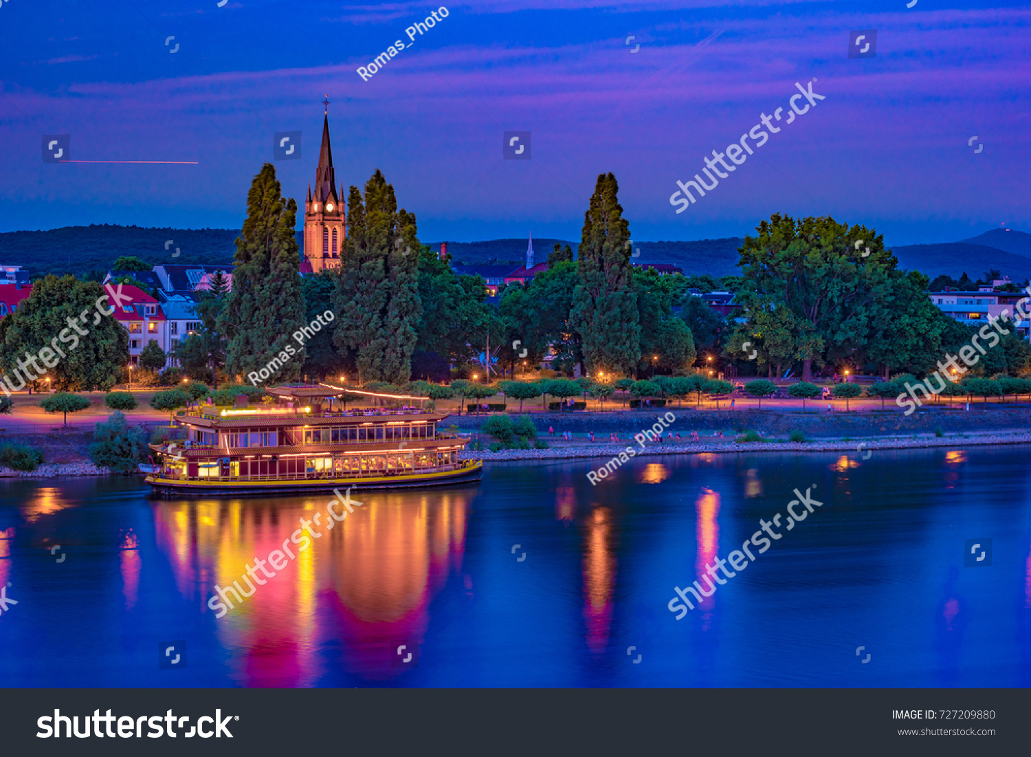 Skyline of Bonn, Germany. Beautiful night shot of great german city. Panorama with boat, trees, and historic architecture reflected in the water. #727209880