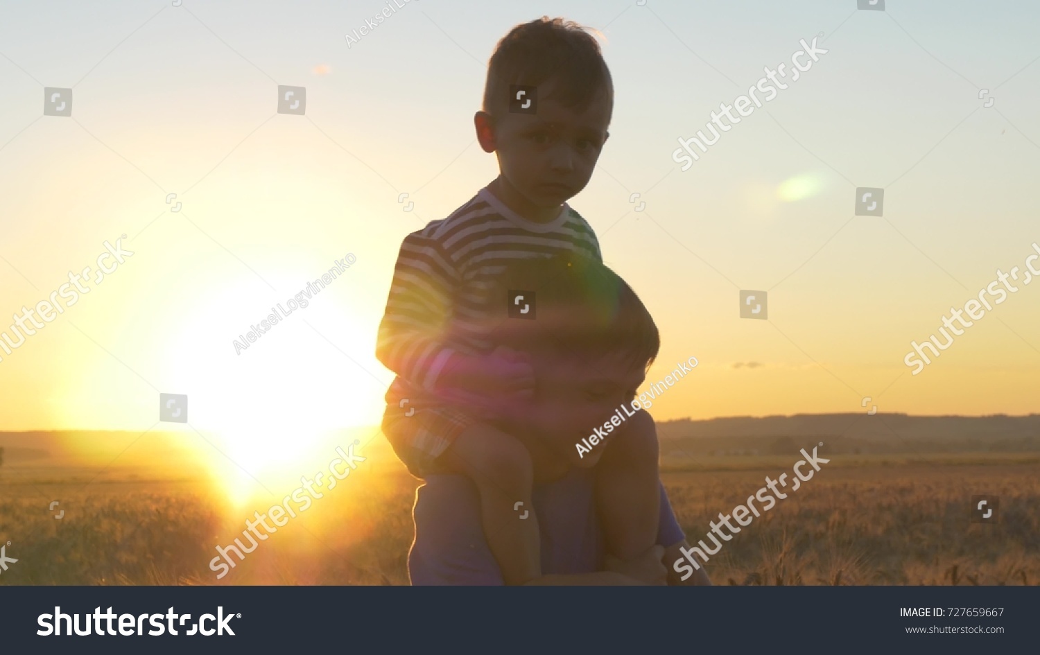 Two boys playing at sunset in a wheat field among golden spikelets #727659667