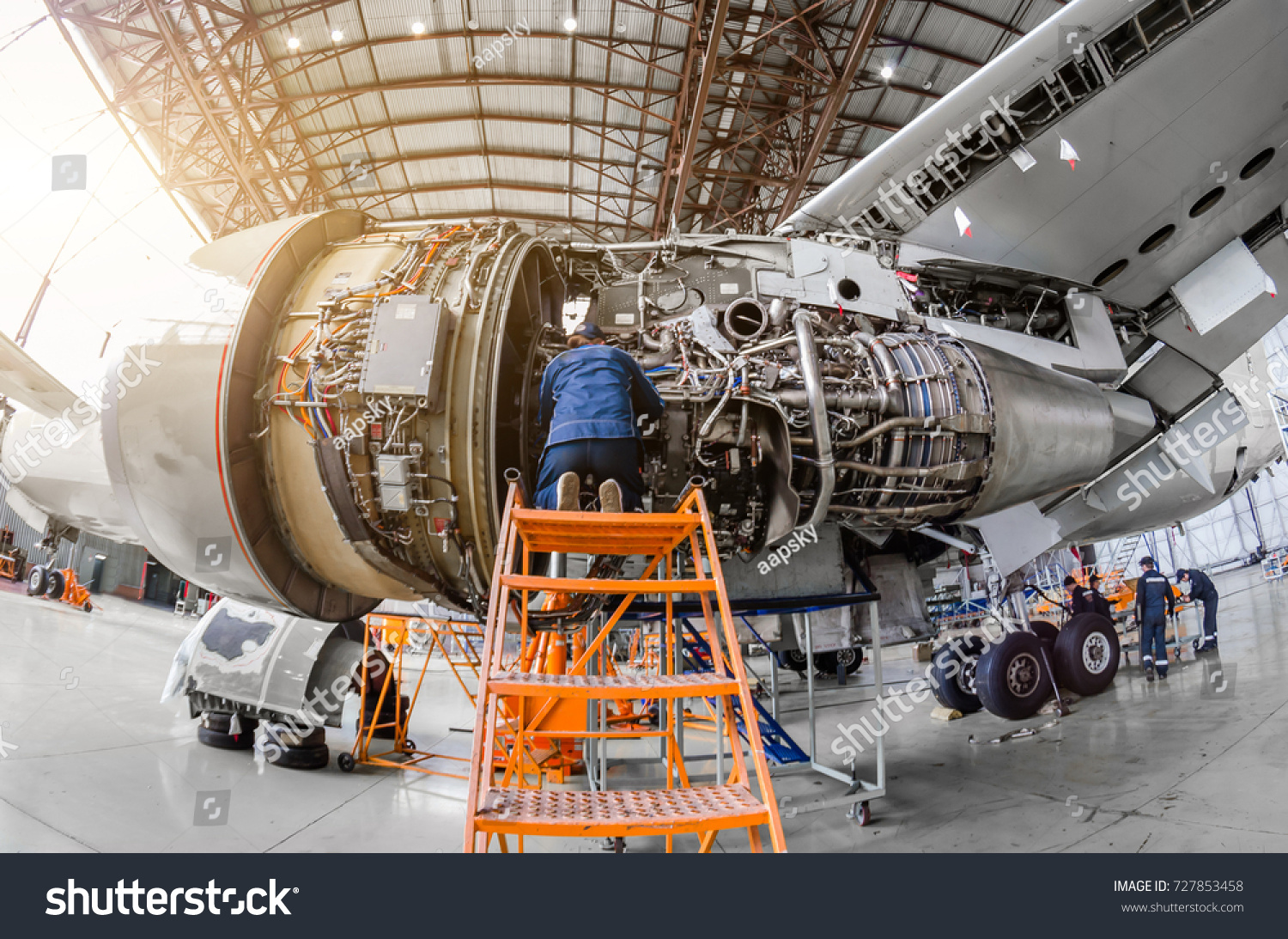 Specialist mechanic repairs the maintenance of a large engine of a passenger aircraft in a hangar #727853458