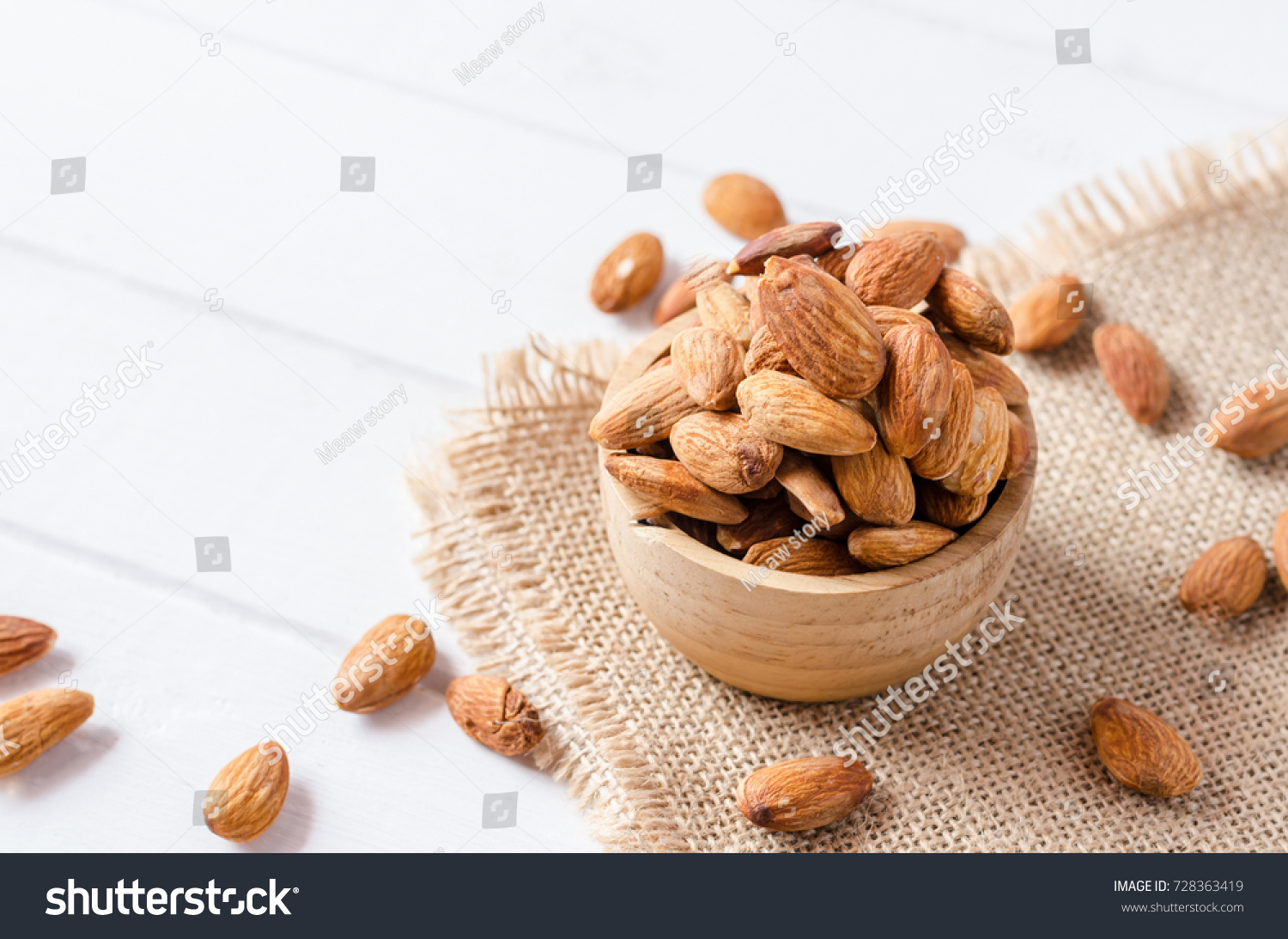 Almonds in bowl on white wooden background #728363419