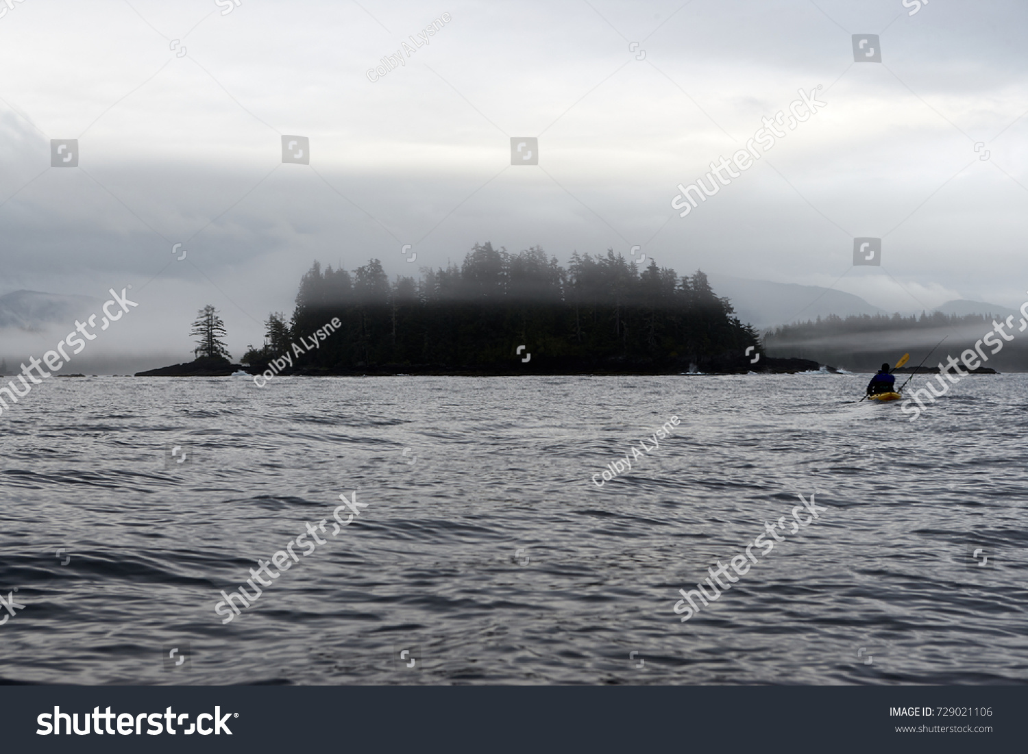Kayaker paddling near small woody island at Foggy Bay, Alaska, USA #729021106