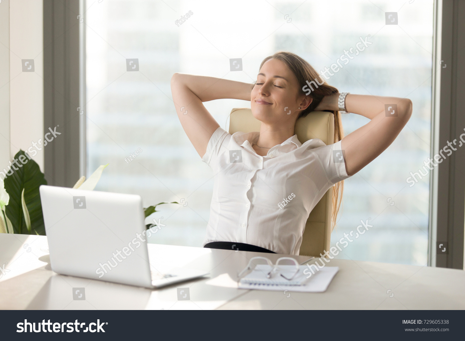 Calm smiling businesswoman relaxing at comfortable office chair hands behind head, happy woman resting in office satisfied after work done, enjoying break with eyes closed, peace of mind, no stress #729605338