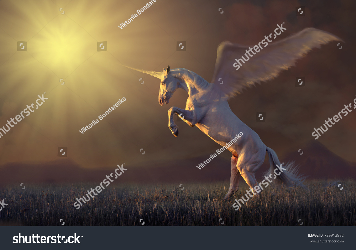 Pink unicorn with the wings reared in the grass on mountains background #729913882