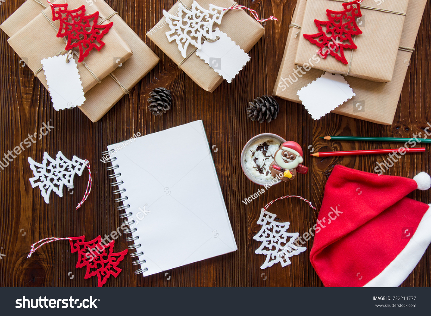 Preparation for the New Year holidays concept, gifts, New Year's decor, notebook, cup of hot chocolate, Santa Claus hat on a wooden background. Horizontal. Top view. #732214777
