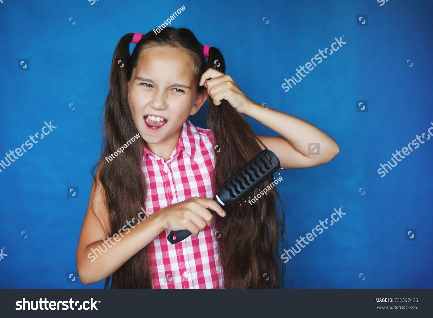 Little girl on a blue background combing her long hair #732397435