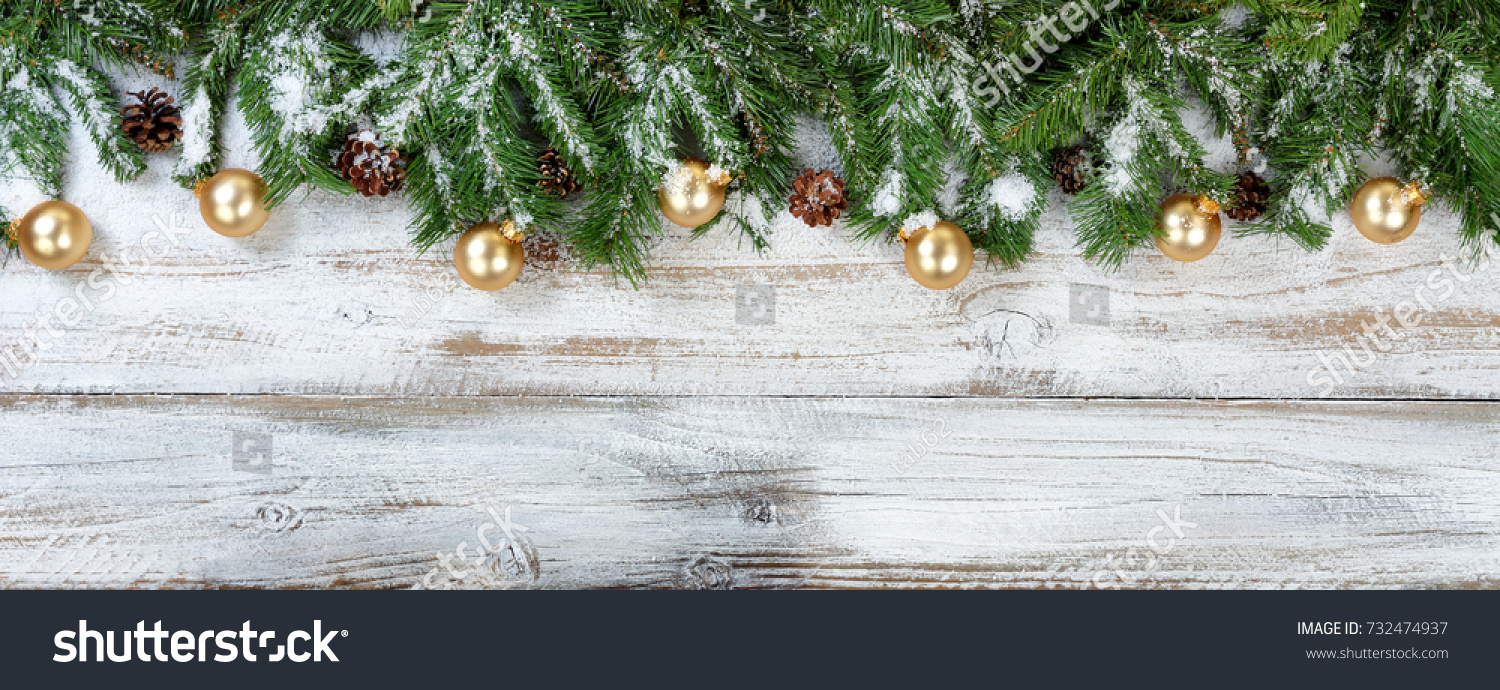 Christmas evergreen branches and golden ornaments on rustic white wood background #732474937