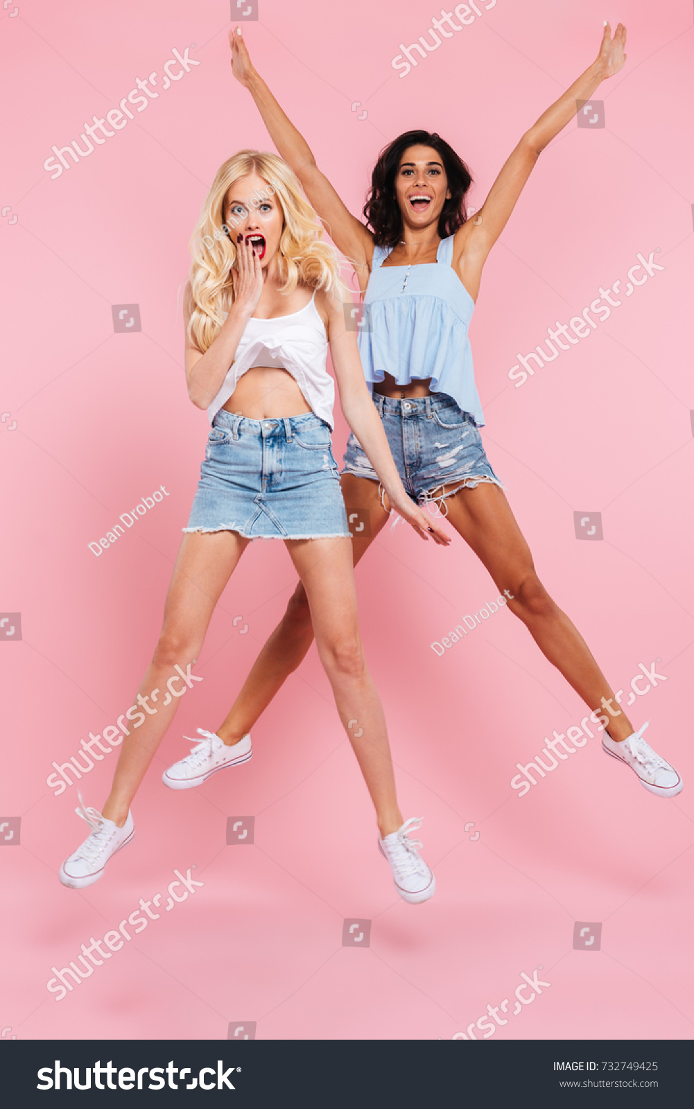 Full-length shot of funny caucasian women friends in casual jumping and looking camera isolated #732749425