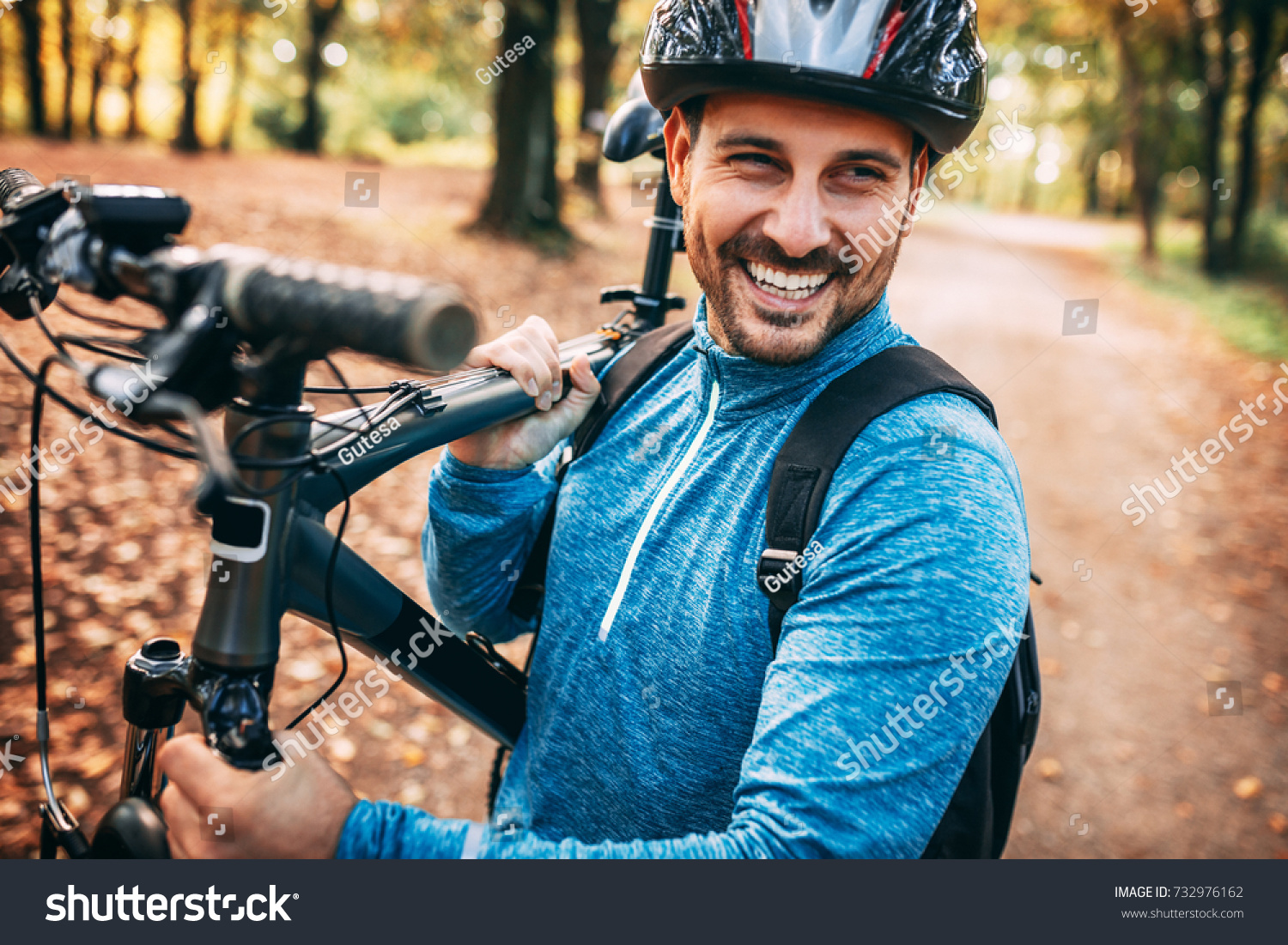 Young pretty athletic man standing with bicycle in autumn park. #732976162
