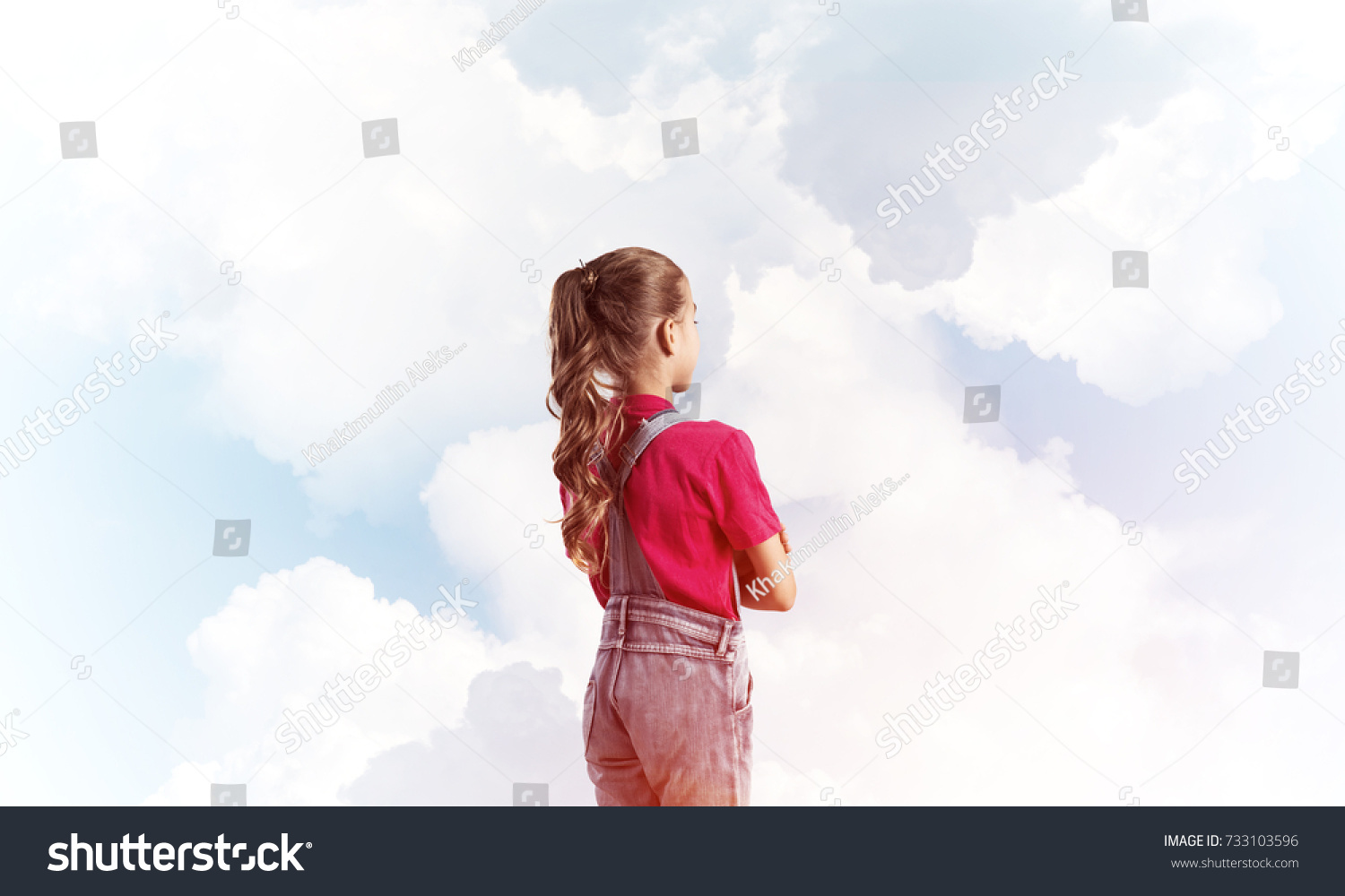 Little cute girl in overalls against sky background dreaming about future #733103596