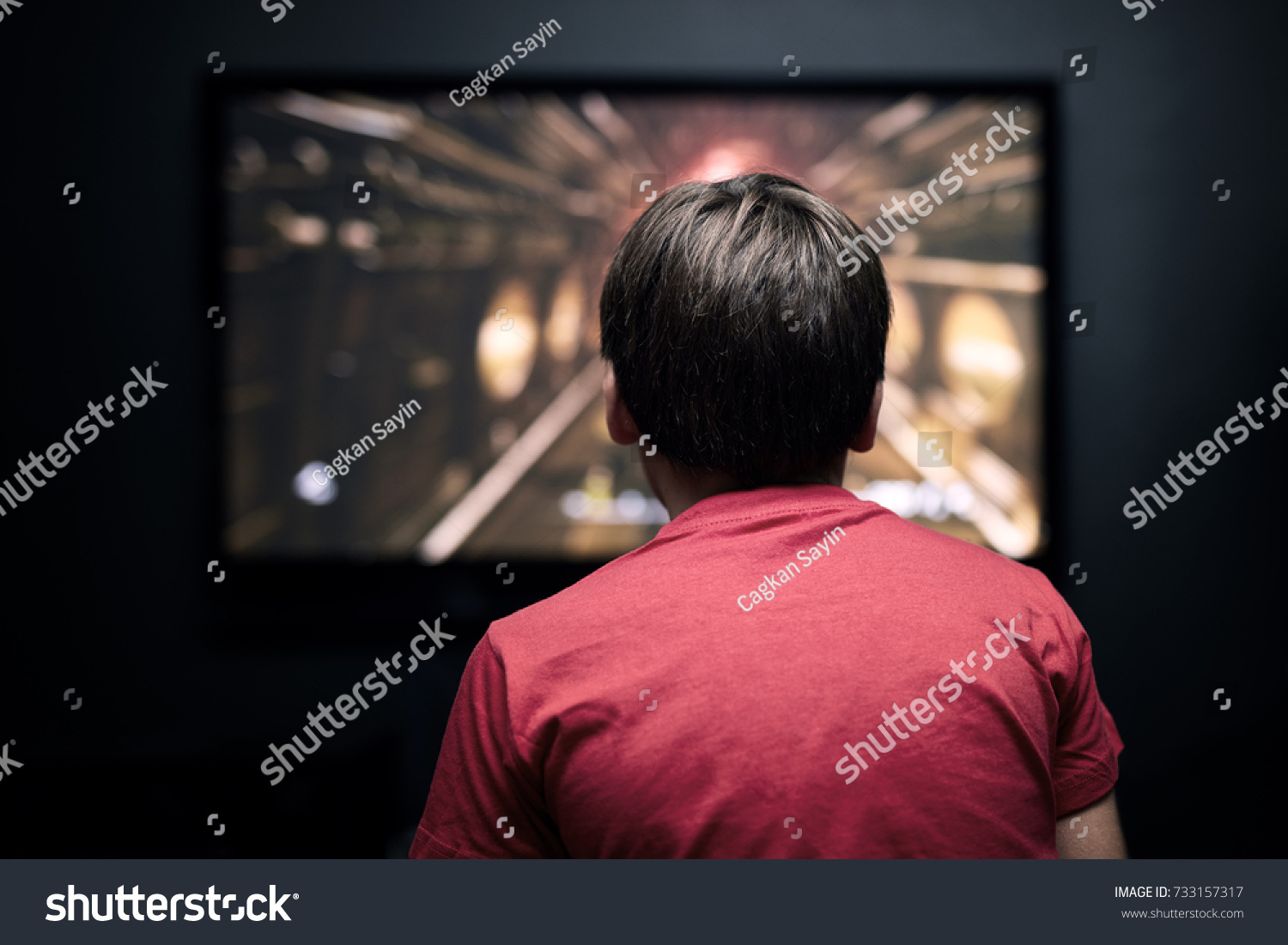 Facing back caucasian little boy watching television. Television and video game addiction. #733157317