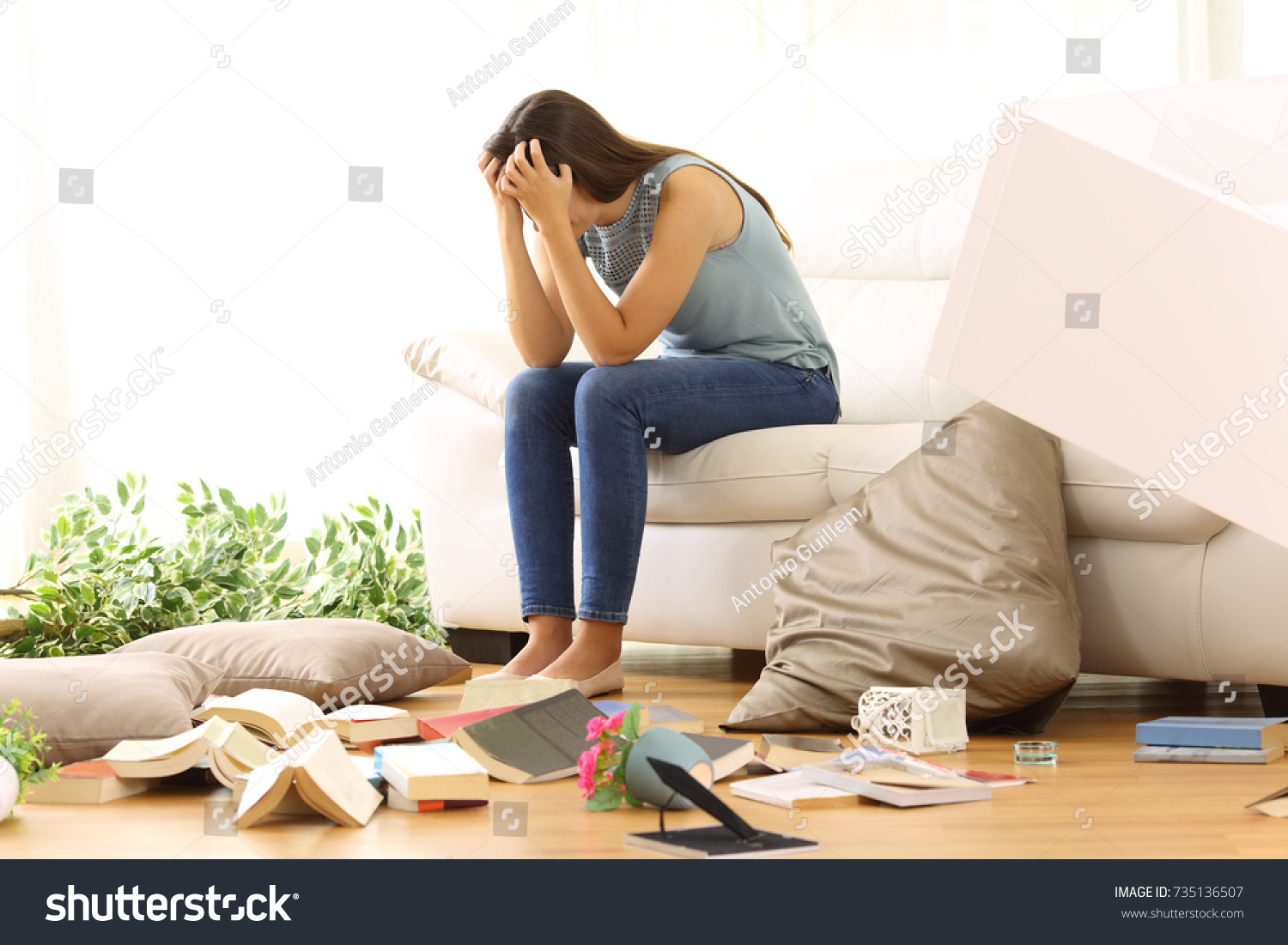 Desperate homeowner complaining after home robbery sitting on a couch of the messy living room at home #735136507