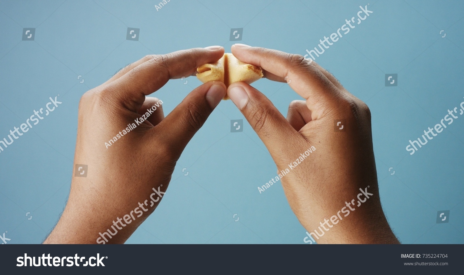 mixed race man's hand open a fortune cookies with an empty paper #735224704
