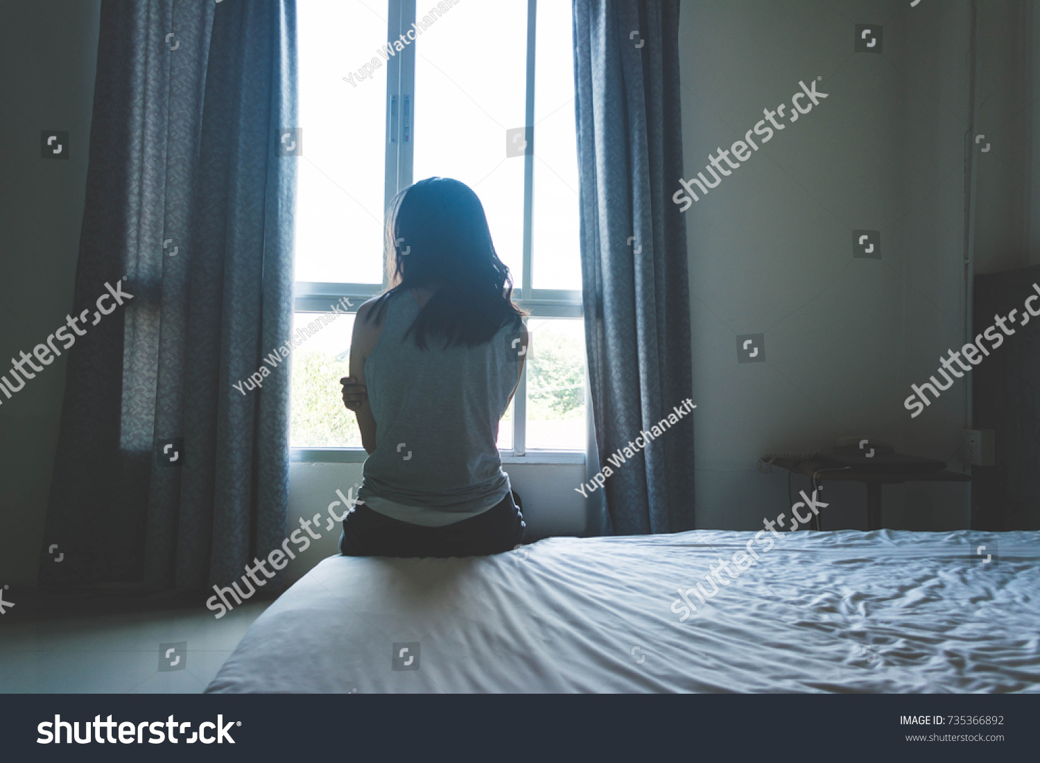 woman sitting on bed in room with light from window abuse concept #735366892