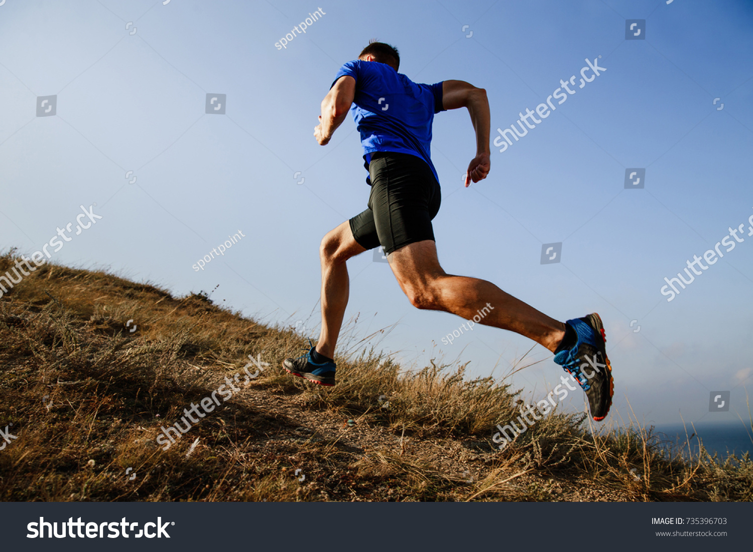 dynamic running uphill on trail male athlete runner side view #735396703