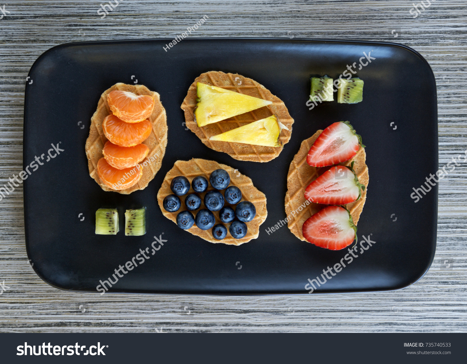 Fruit served on waffles on a black serving dish #735740533
