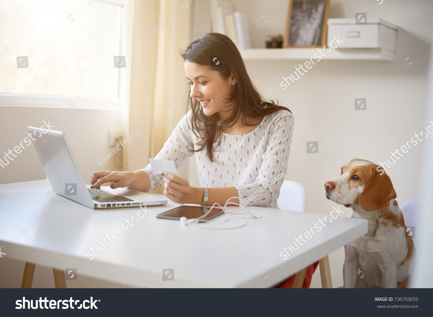 Young Caucasian businesswoman using credit card for on line payment. her dog next to her #736793659