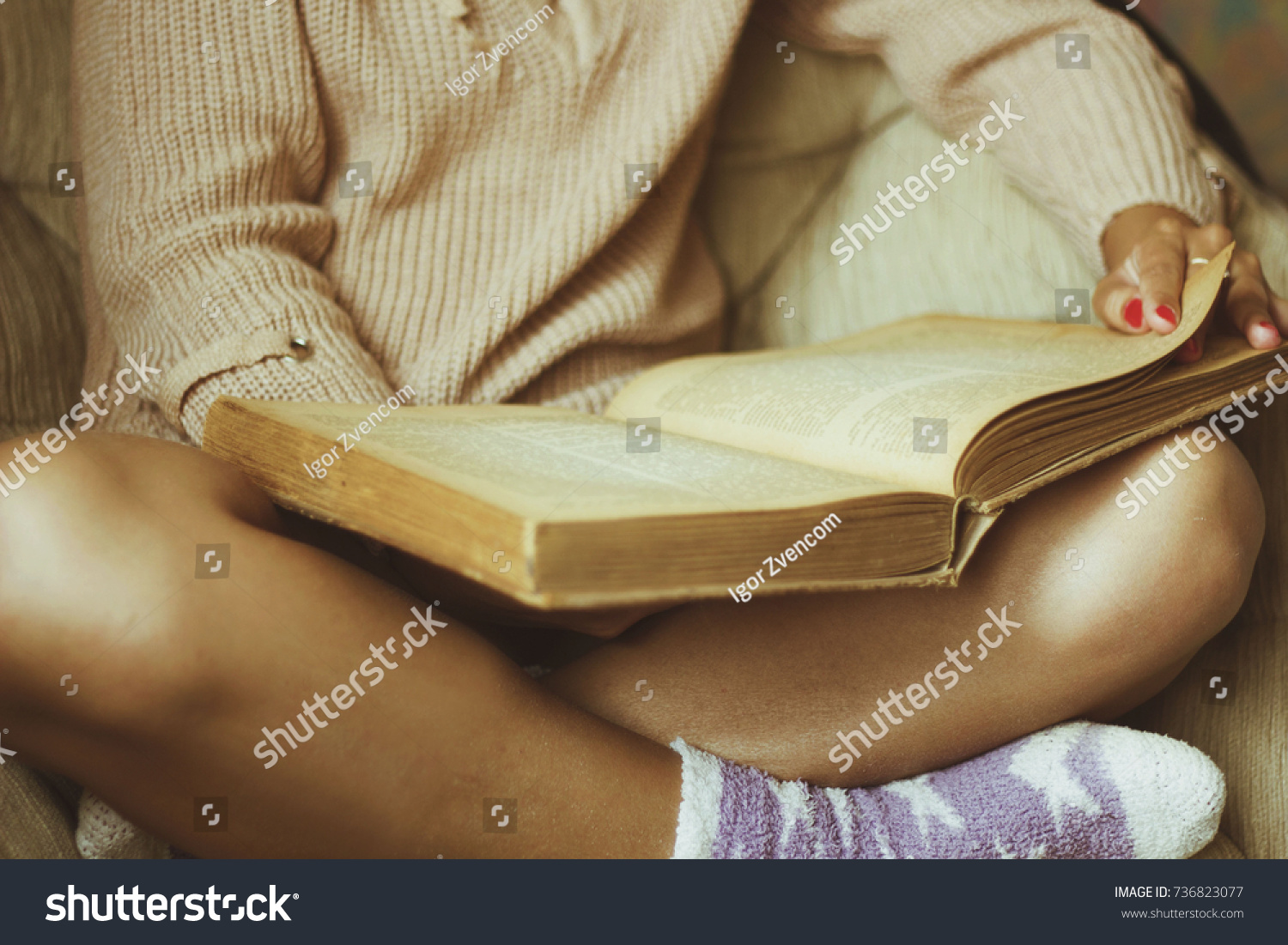 Cute girl on a comfortable chair, reading a book, the concept of comfort and hipster #736823077