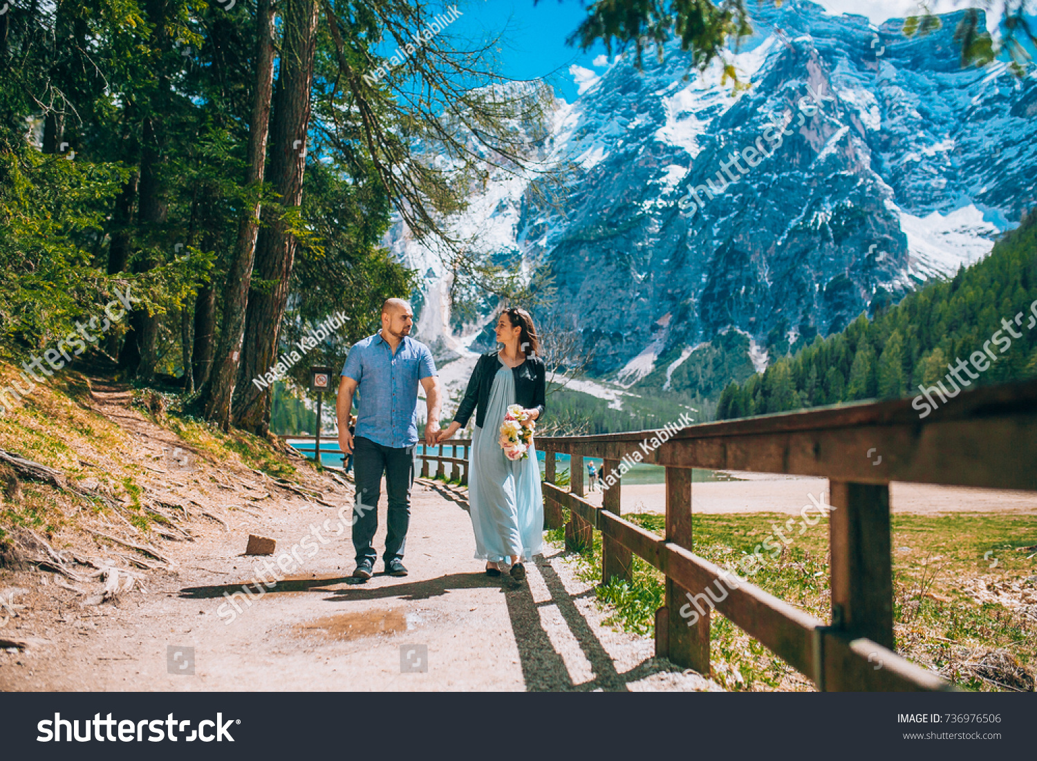 Young Couple against lake, summer park. lago di braies,Dolomite,Italy. Man and woman on vacation in beautiful place. #736976506