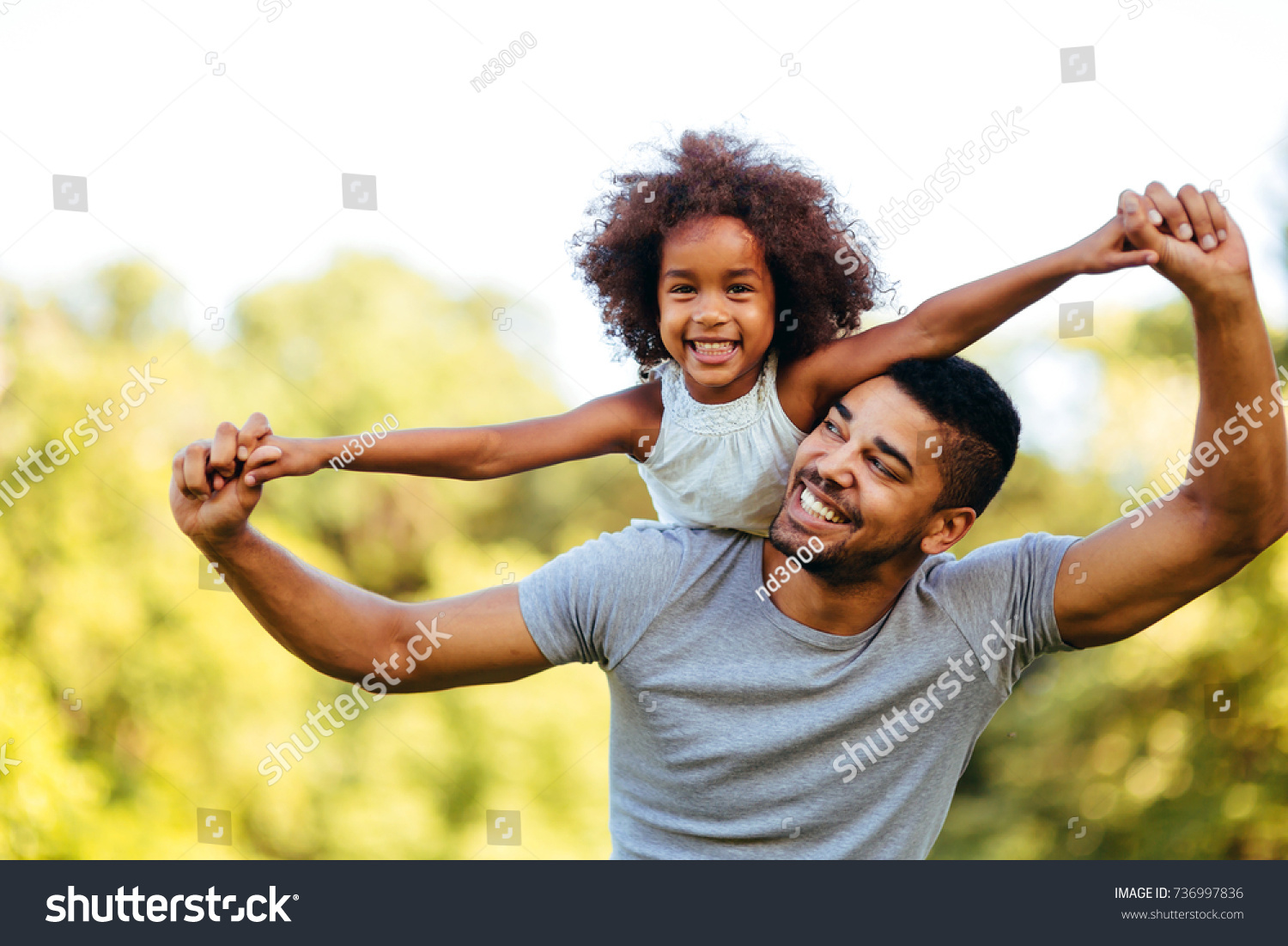 Portrait of young father carrying his daughter on his back #736997836