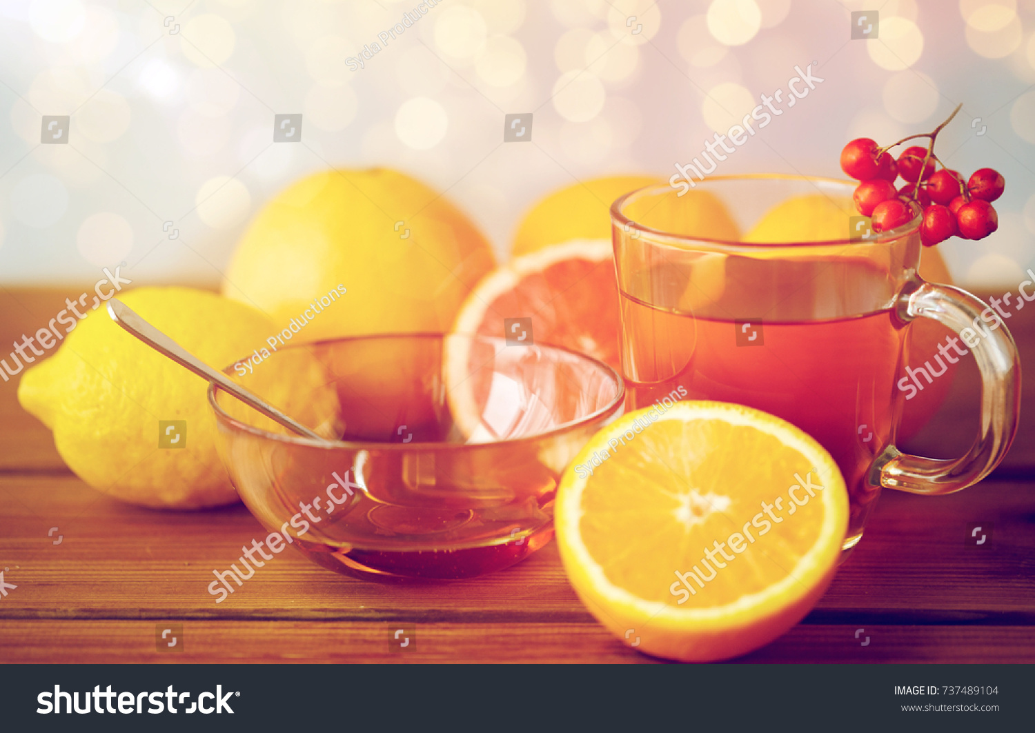 health, traditional medicine, folk remedy and ethnoscience concept - cup of tea with honey, lemon and rowanberry on wooden background #737489104