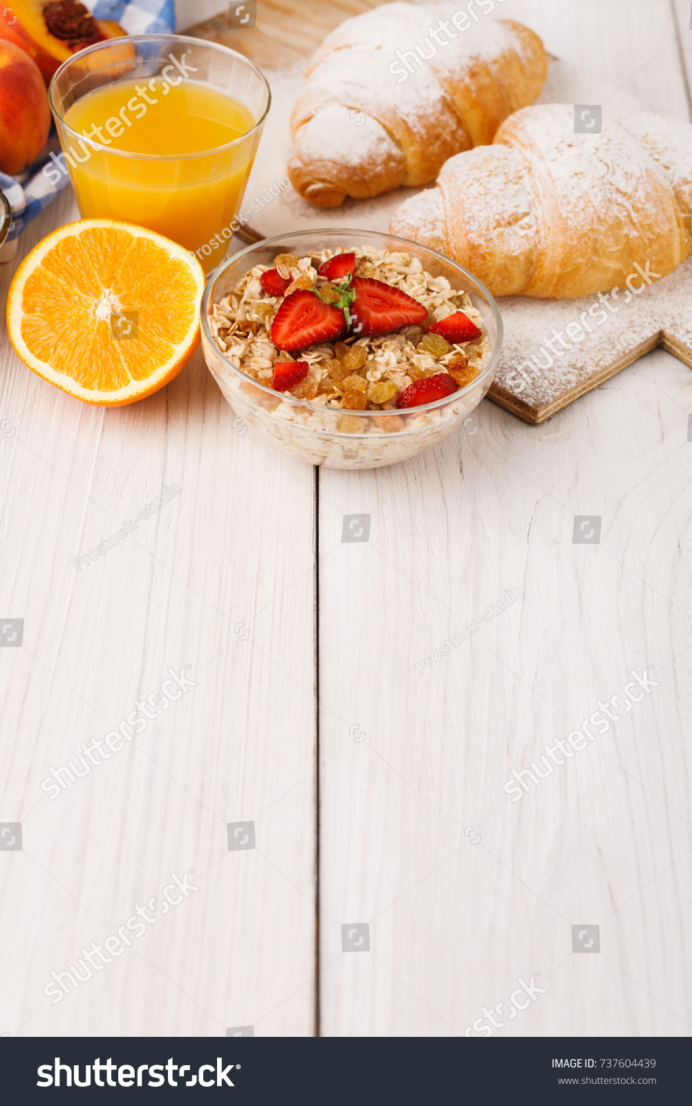 Traditional french breakfast menu . Yogurt with fresh berries, glass of orange juice, muesli and croissants on wooden table, copy space #737604439