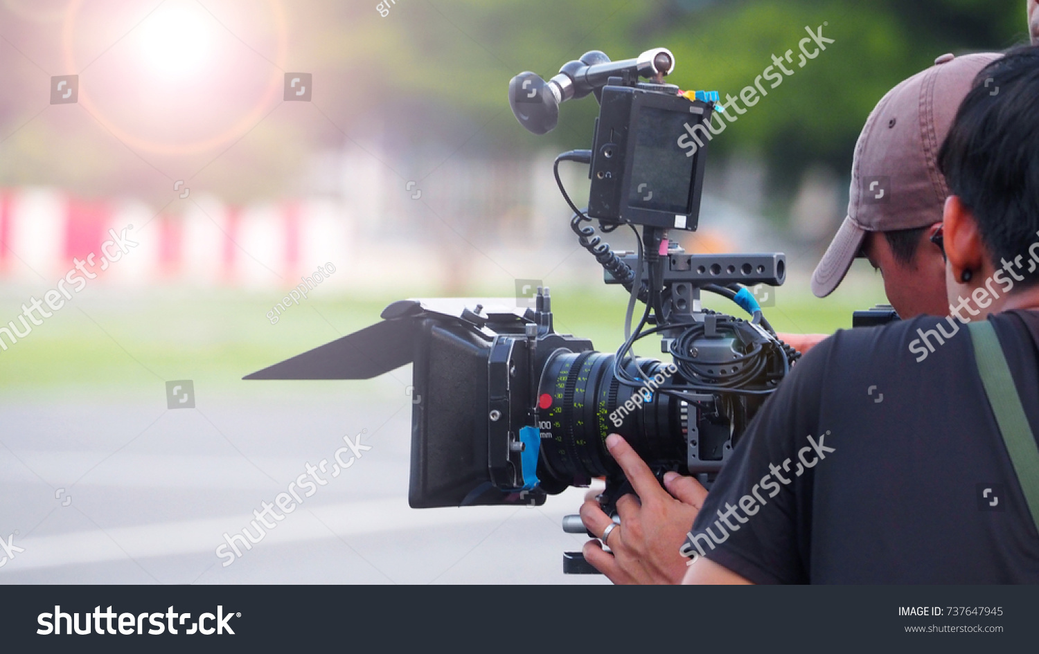 Blurry image of movie shooting or video production and film crew team with camera equipment at outdoor location and light flare effect.  #737647945