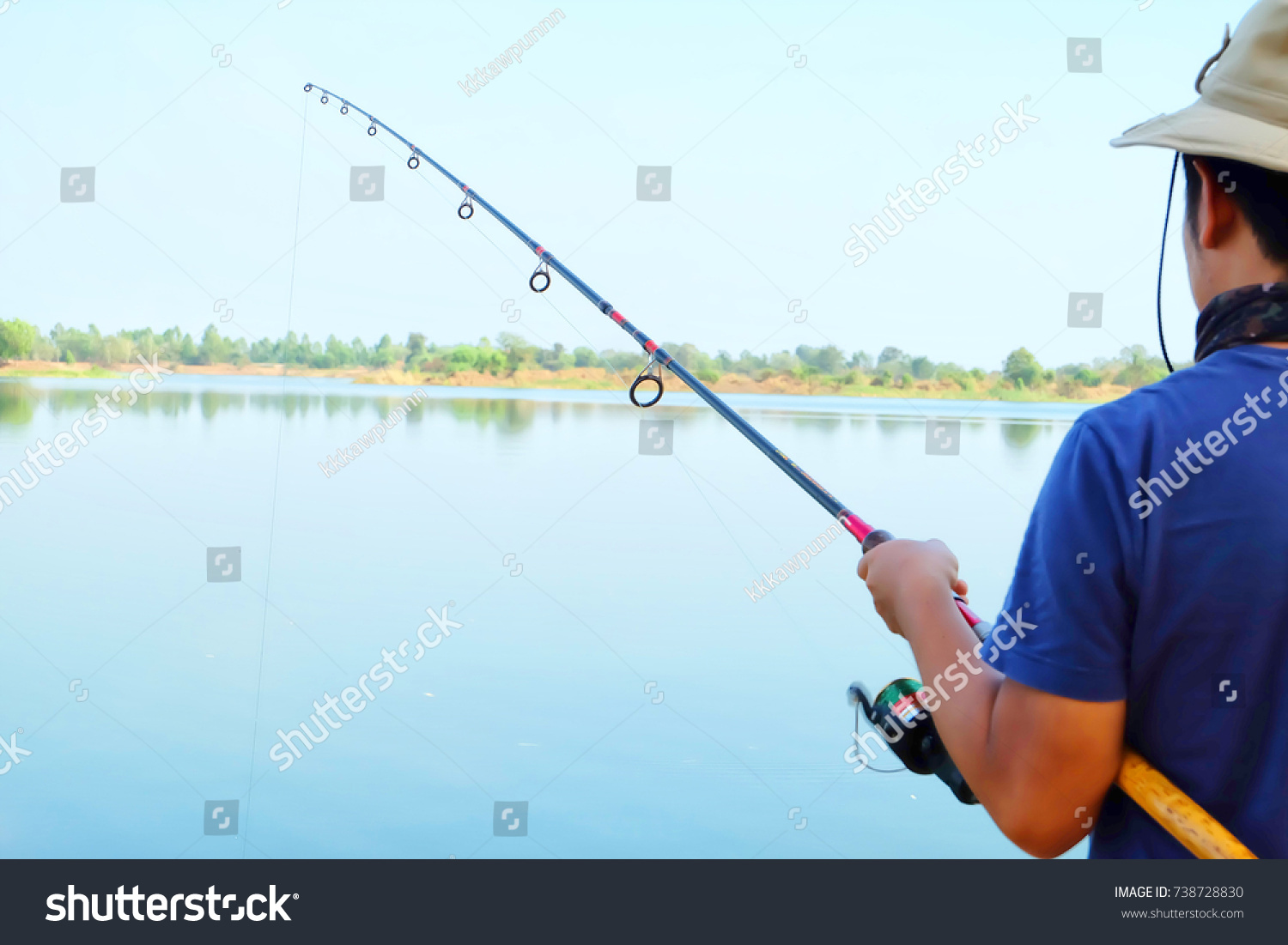 Young man fishing at lake, Fishing as recreation and sports displayed by fisherman at lake #738728830
