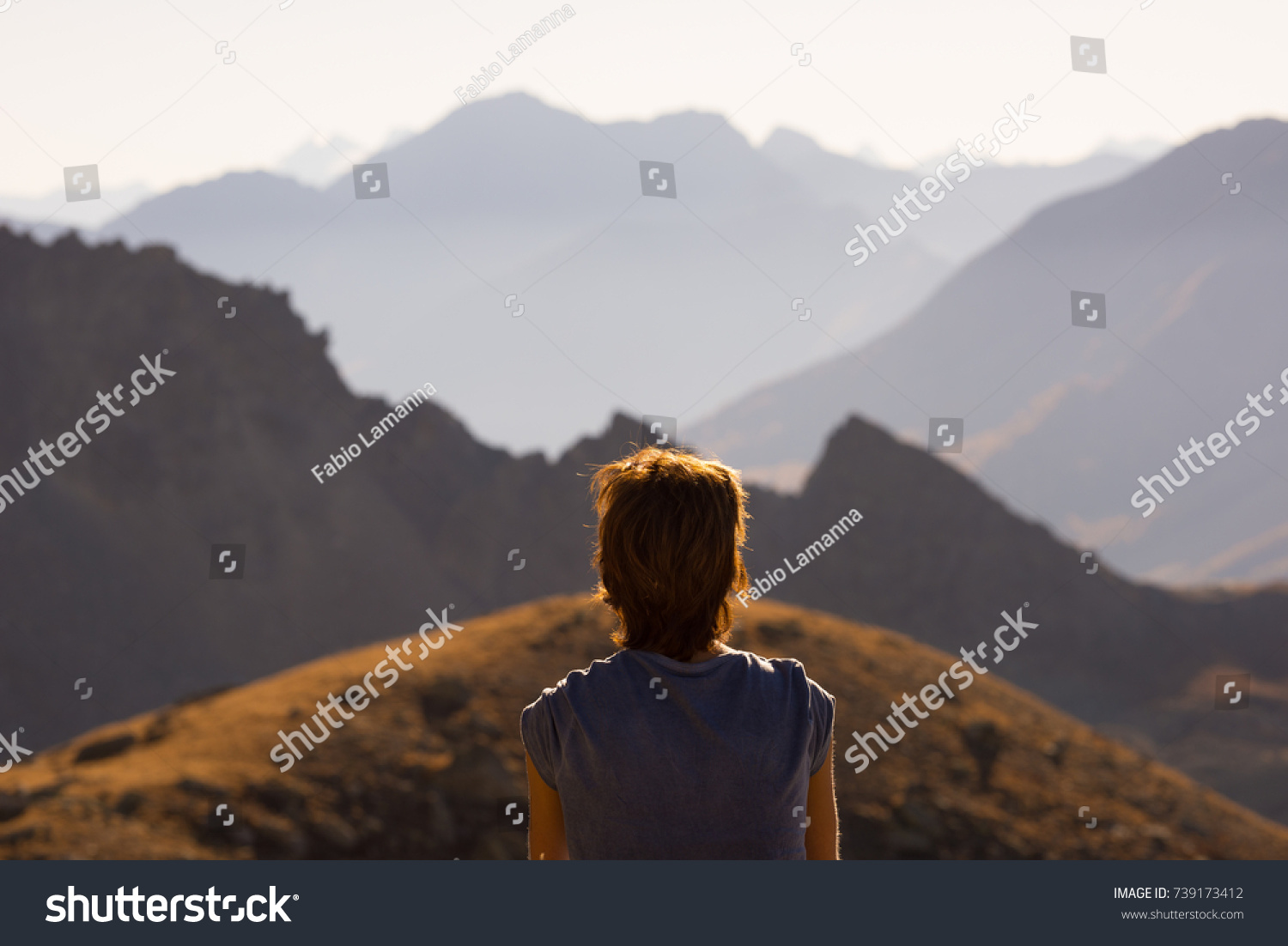 One person looking at view high up on the Alps. Expasive landscape, idyllic view at sunset. Rear view. #739173412