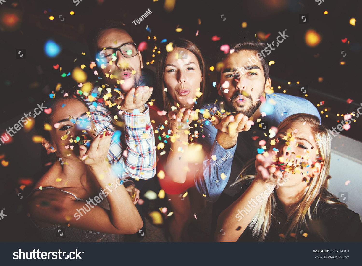 Group of people having a party, blowing confetti  #739789381