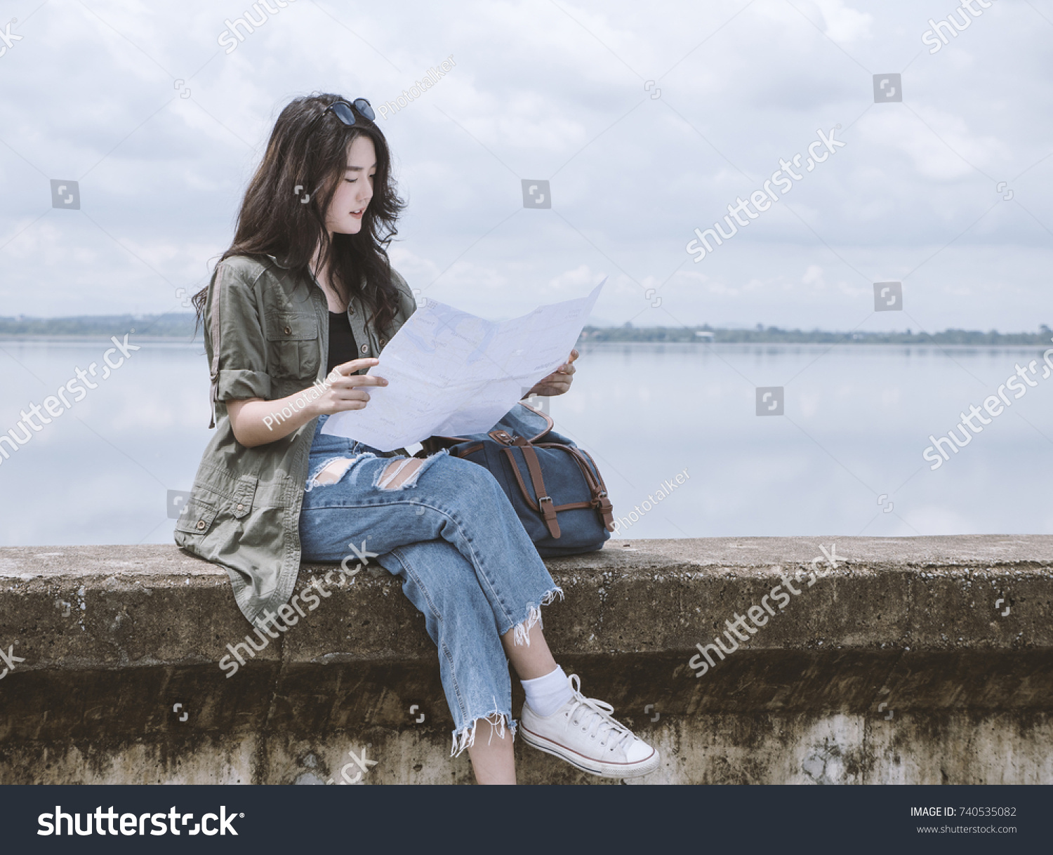 Young asian woman tourist sitting and watching map beside road with copy space, beautiful backpacker tourism feeling relax in her vacation. Traveling, vacation concepts. #740535082