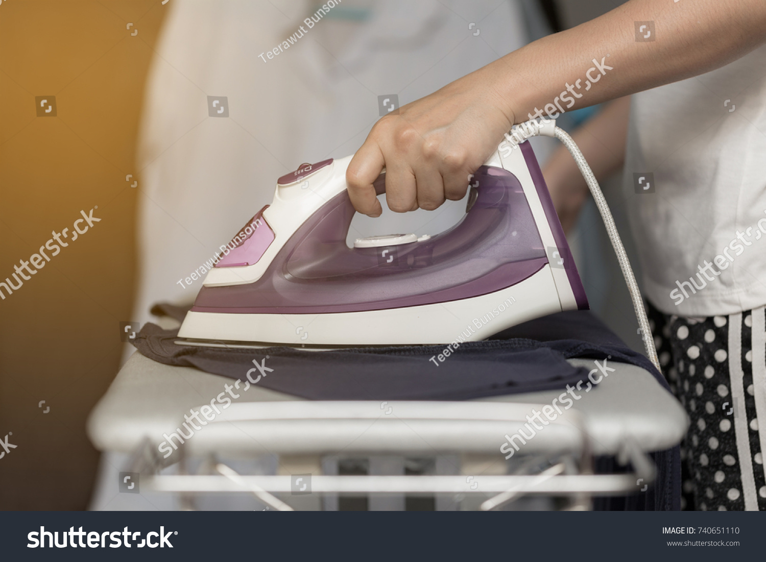 Young woman is using steam iron on her cloths #740651110