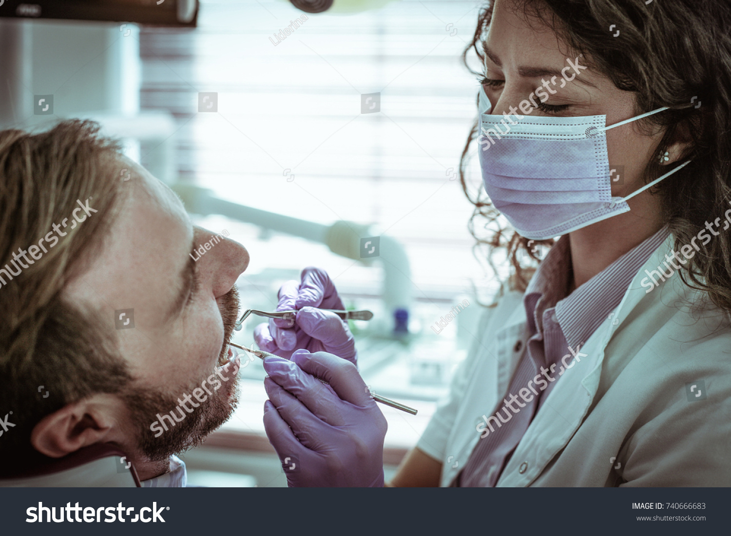 Female dentist examining young man.  #740666683