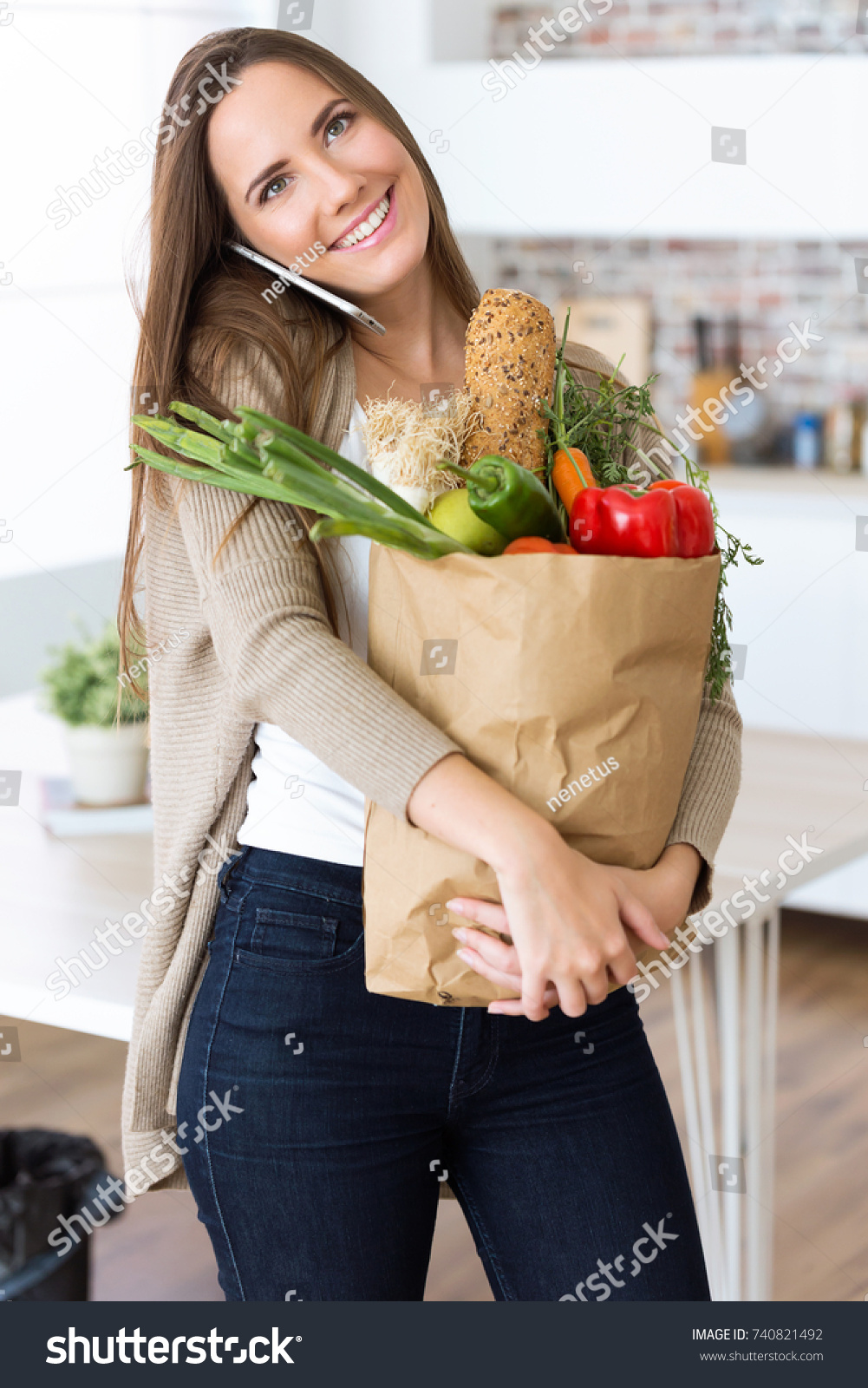 Portrait of beautiful young woman with vegetables in grocery bag at home. #740821492