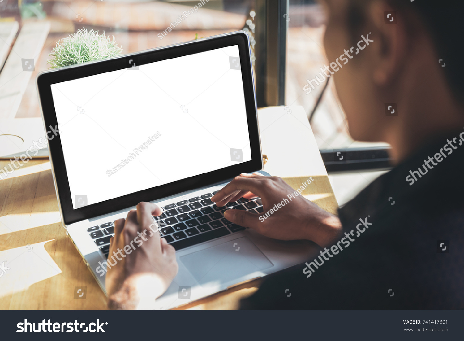 Young man working on his laptop with blank copy space screen for your advertising text message in office, Back view of business man hands busy using laptop at office desk #741417301