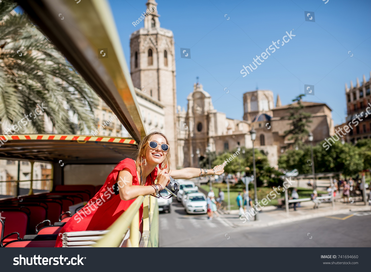 Young happy woman tourist in red dress having excursion in the open touristic bus in Valencia city, Spain #741694660