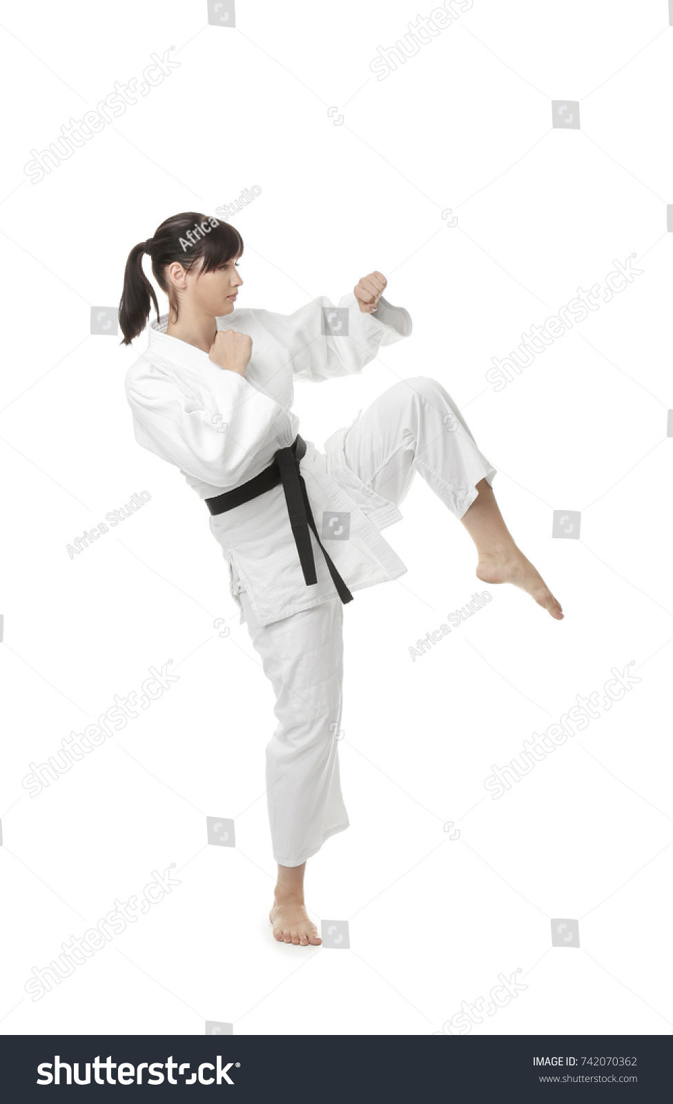 Young woman practicing karate on white background #742070362