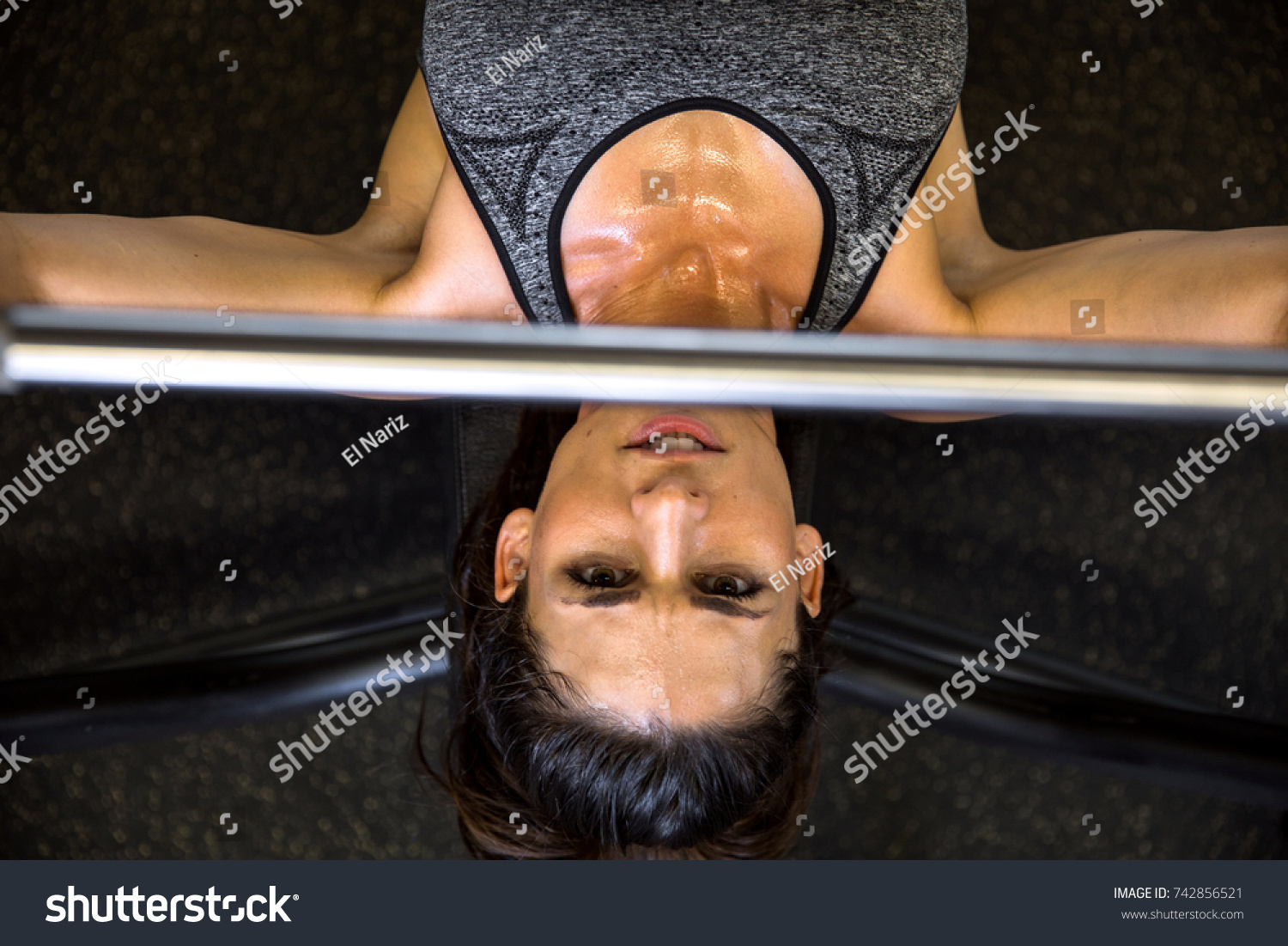 Determined active female athlete pushing bench press bar perspective from above #742856521