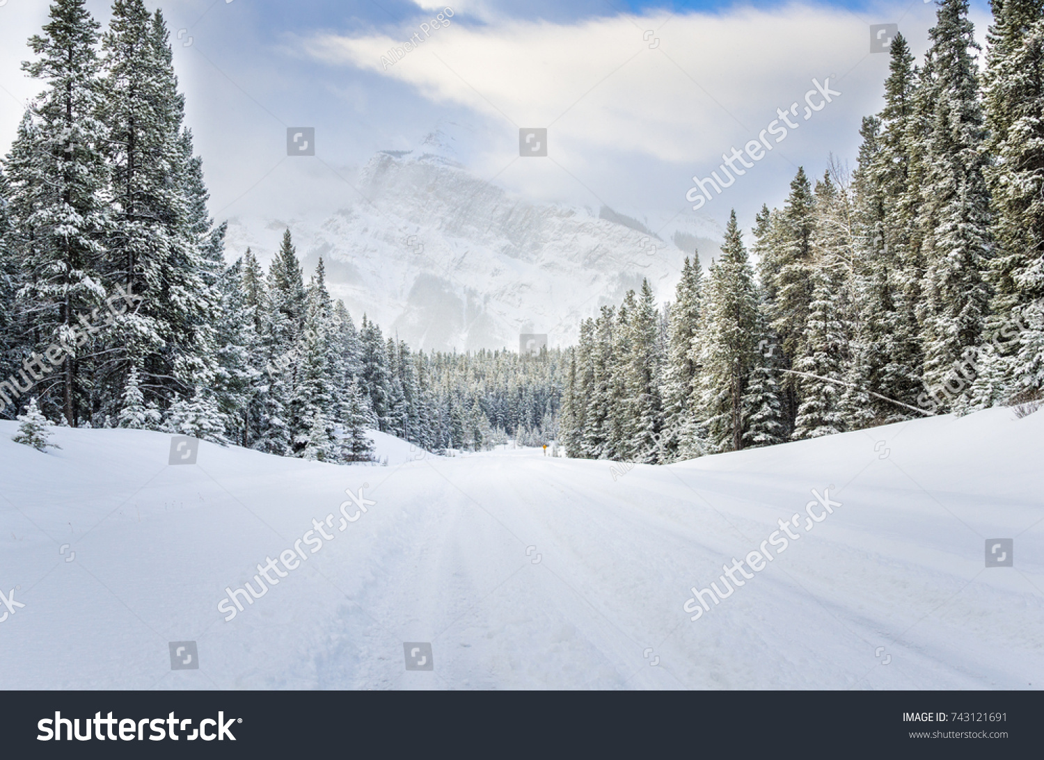 Snowy Road through a Forested Mountain Landscape in Winter #743121691