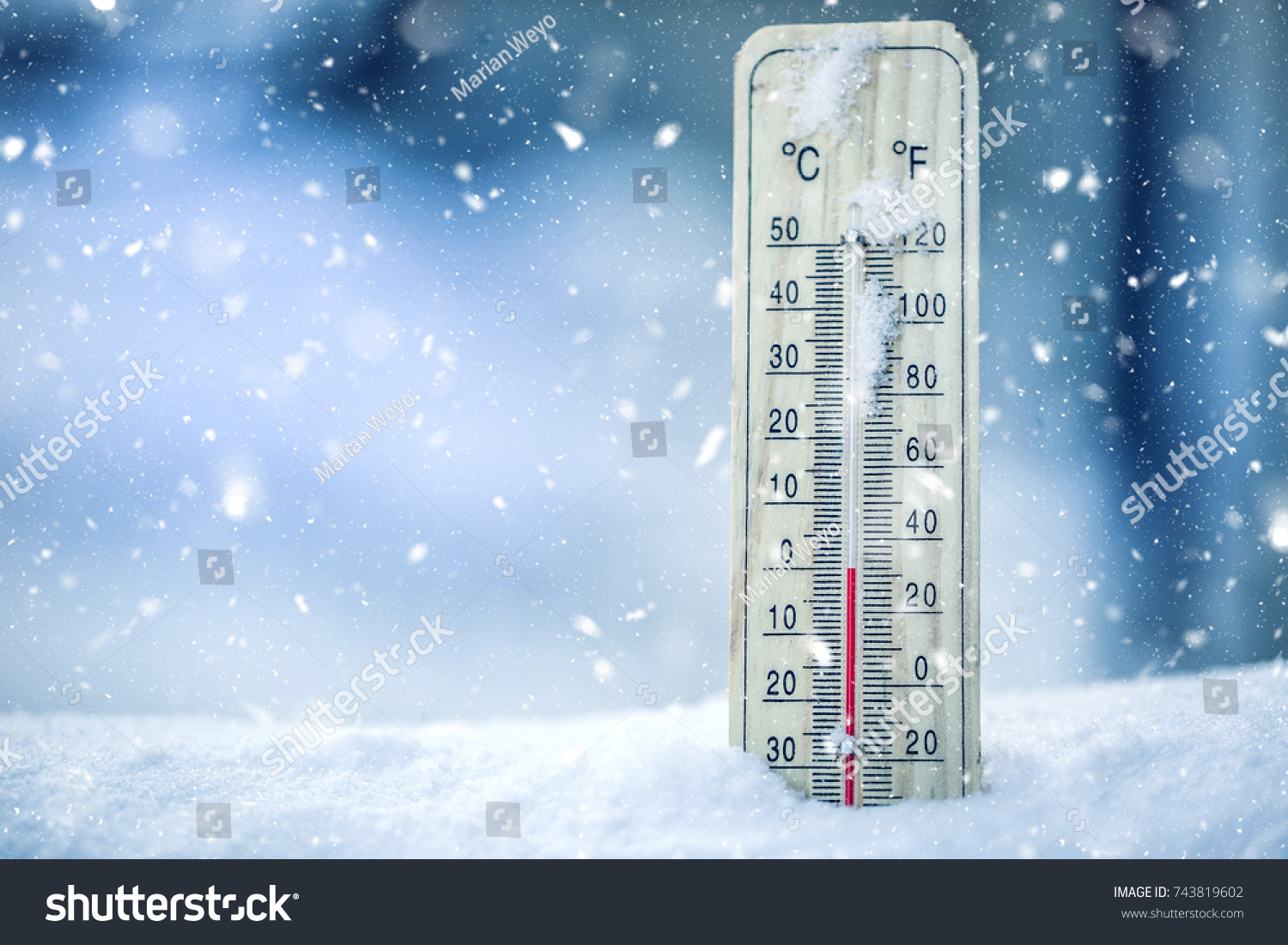 Thermometer on snow shows low temperatures in celsius or farenheit. #743819602